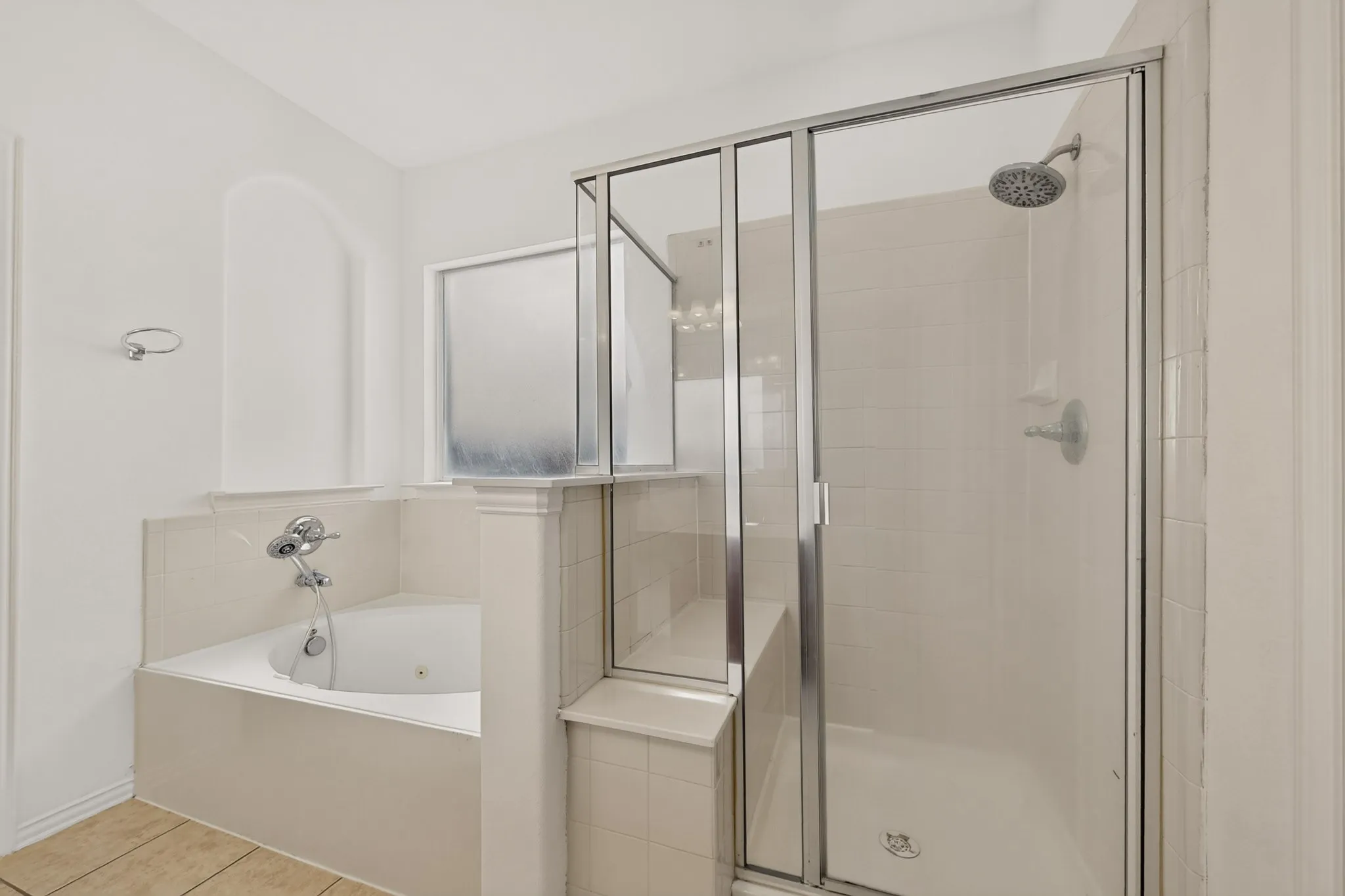 Glass-enclosed shower, jetted soaking tub, tiled shower walls, chrome fixtures, and privacy window