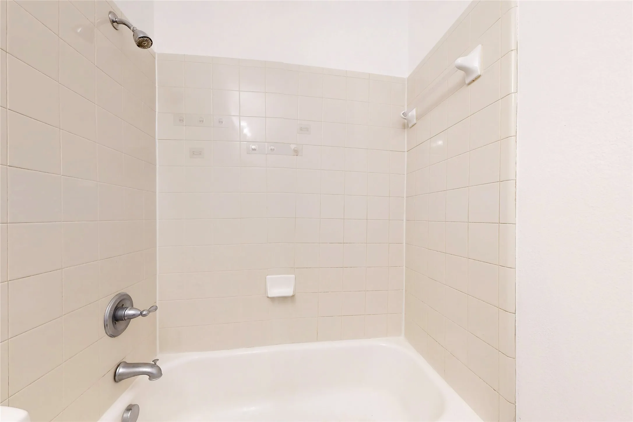 Bathtub with subway tile surround, chrome showerhead, and matching chrome fixtures