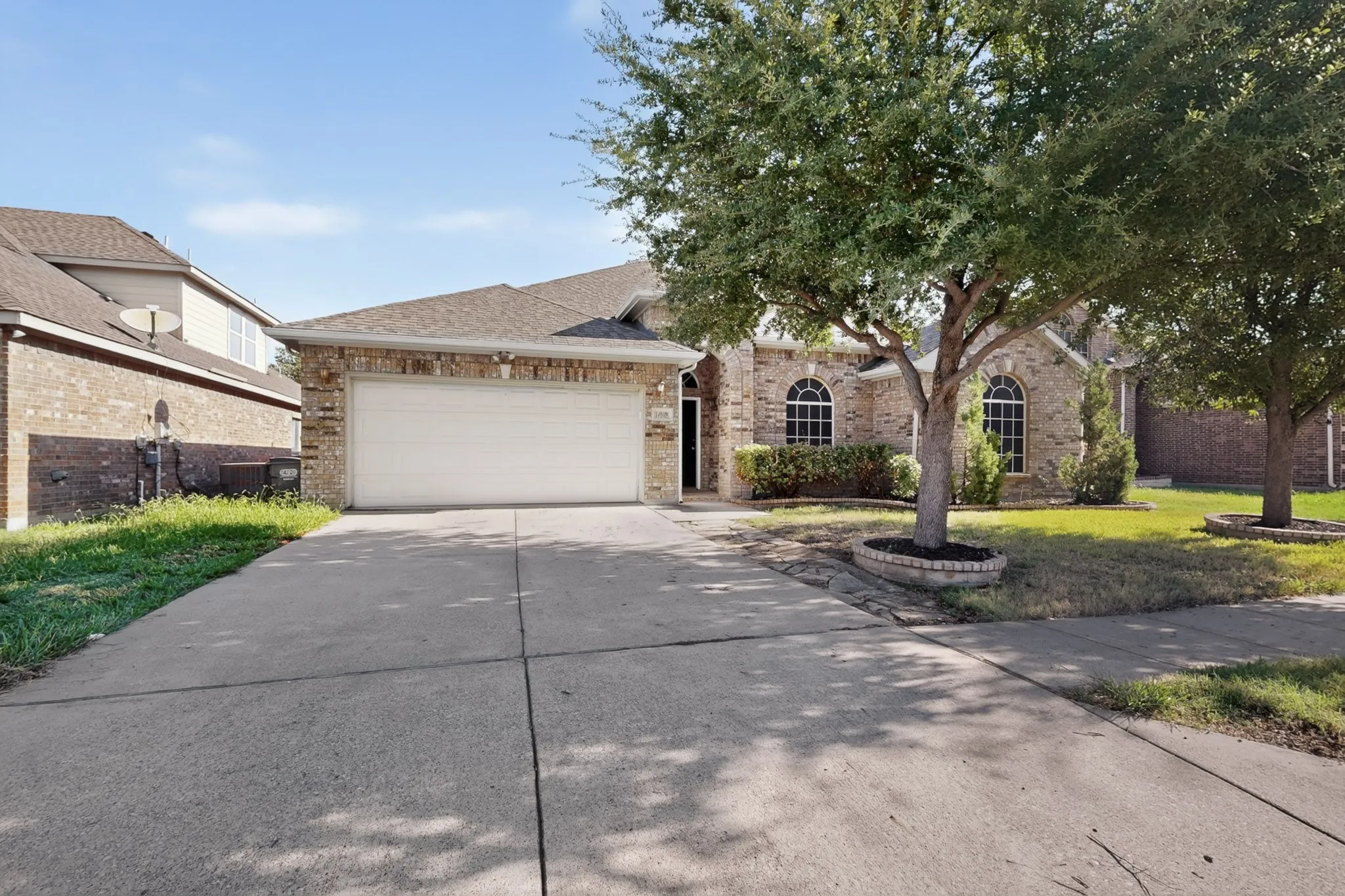 Brick exterior with arched windows, an attached two-car garage, and a concrete driveway