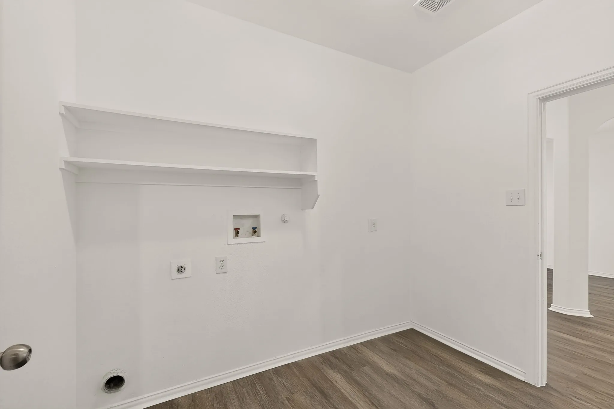 Laundry space featuring built-in shelving, wood-finish flooring, and crisp white walls
