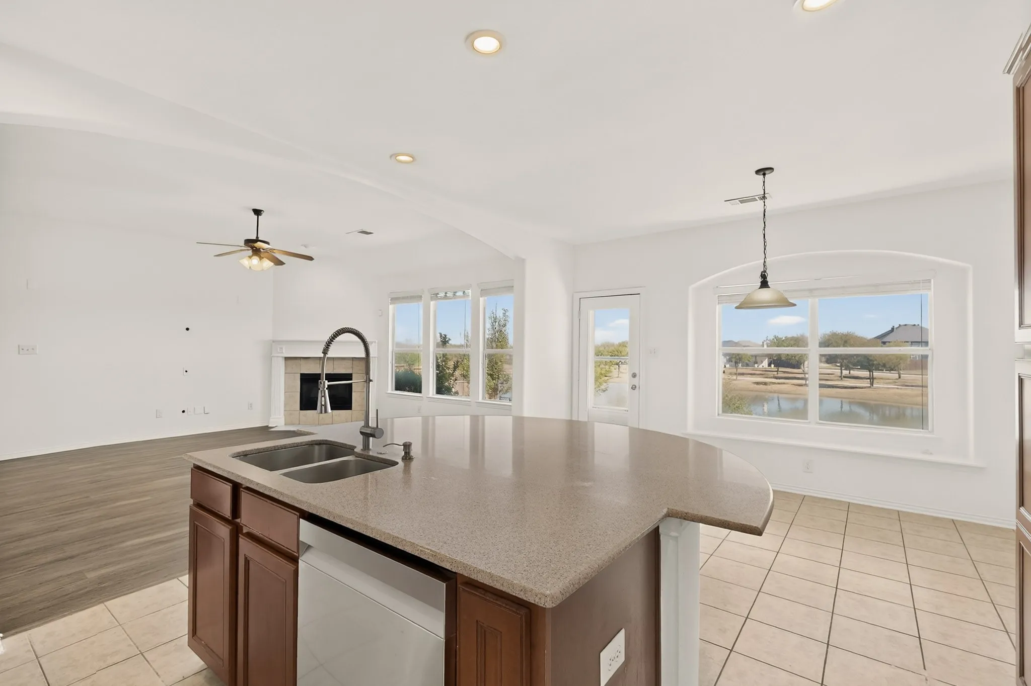 Spacious kitchen island with a double basin sink, solid surface countertop, and wood cabinetry