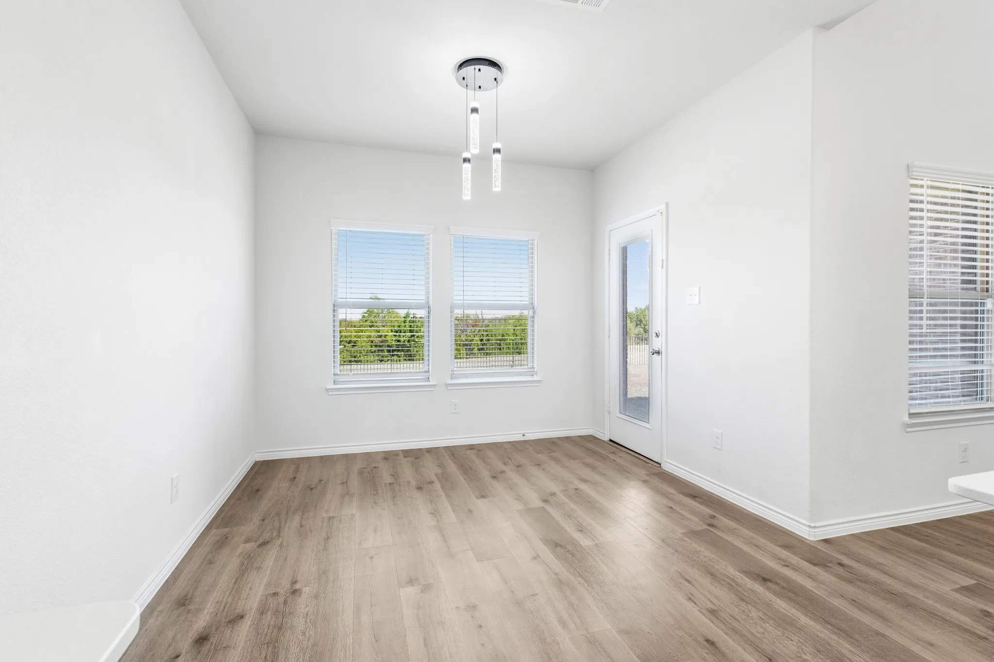 Wood-finish flooring, white walls, and a contemporary chandelier