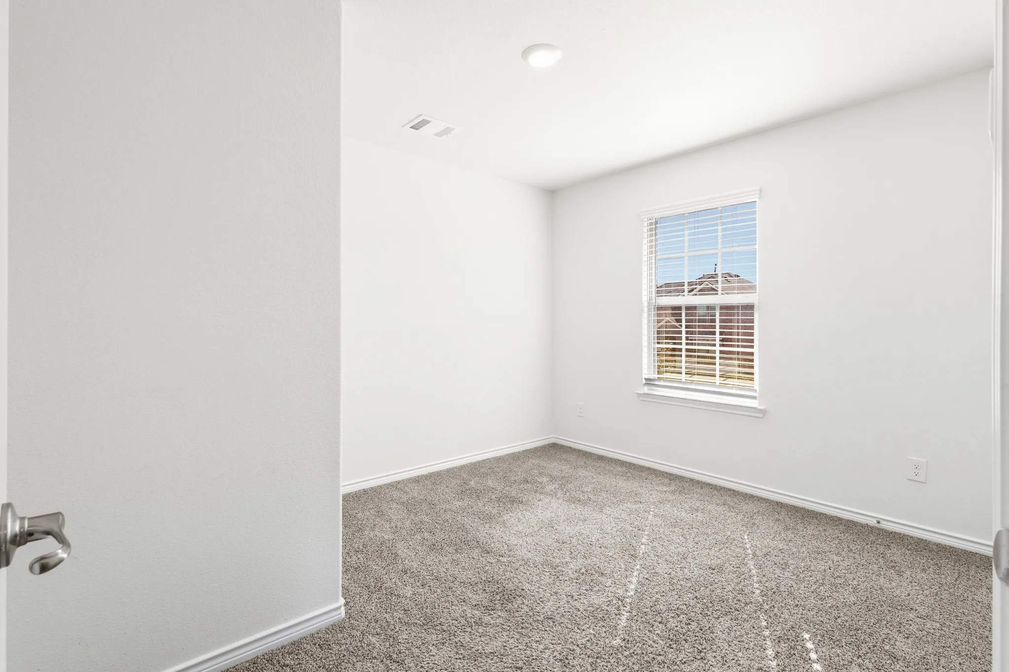 Plush carpeting, neutral wall colors, recessed lighting, and a single window with blinds