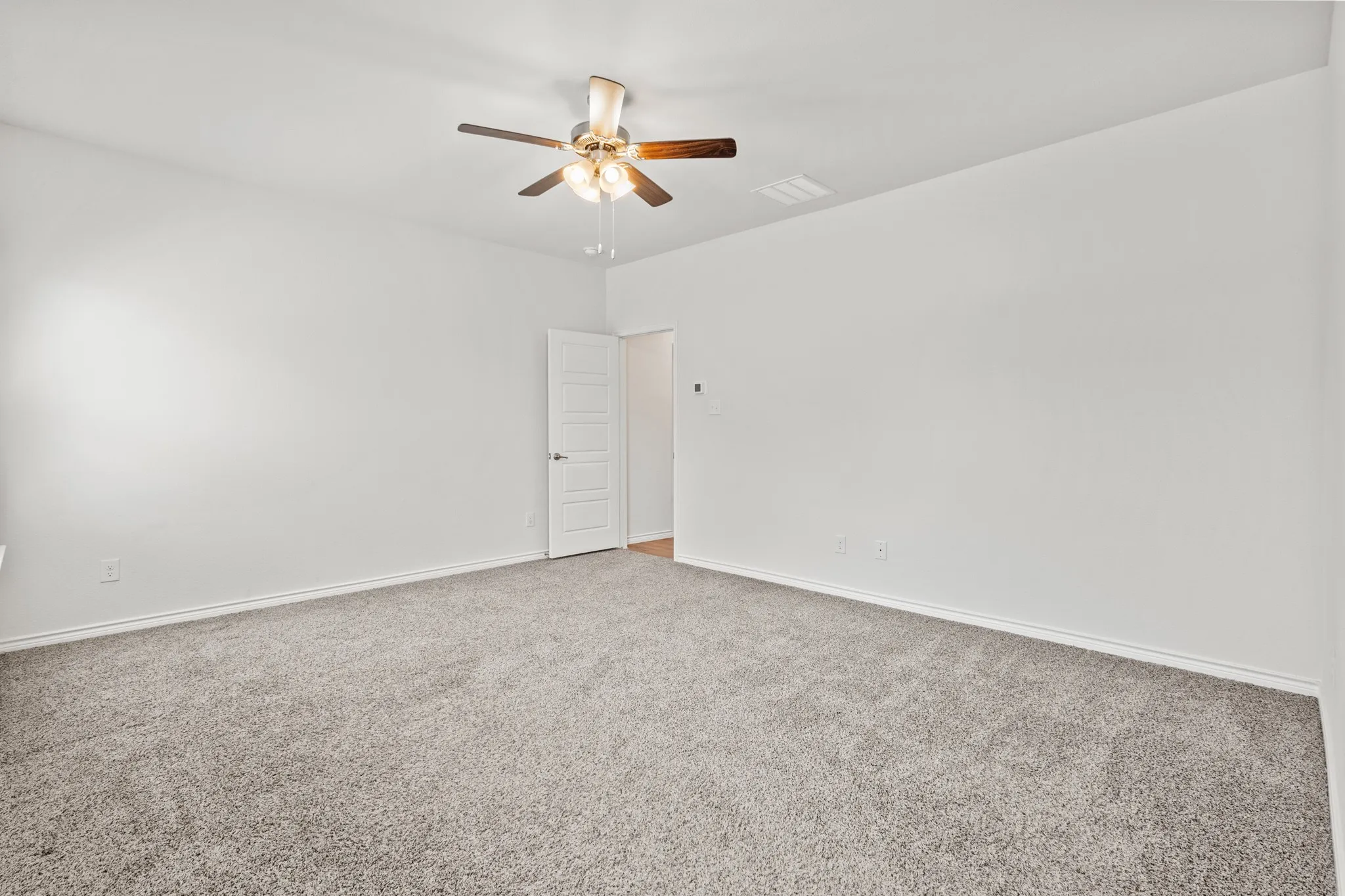 Neutral-toned carpeting, white walls, and a ceiling fan with integrated lighting
