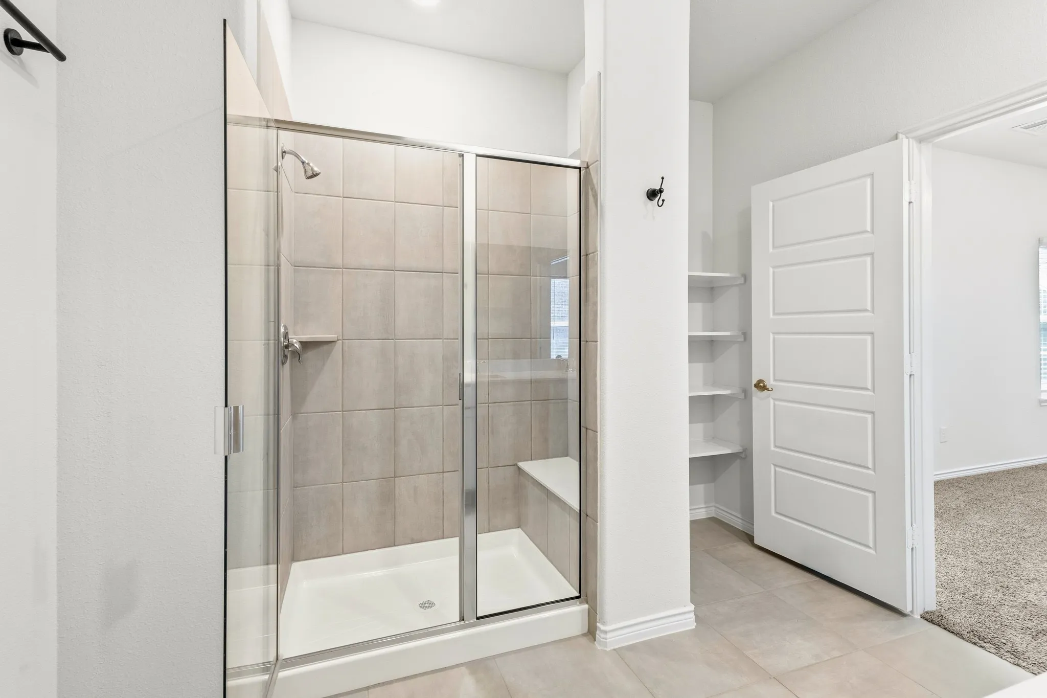 Walk-in shower with clear glass enclosure, integrated bench, and tiled walls