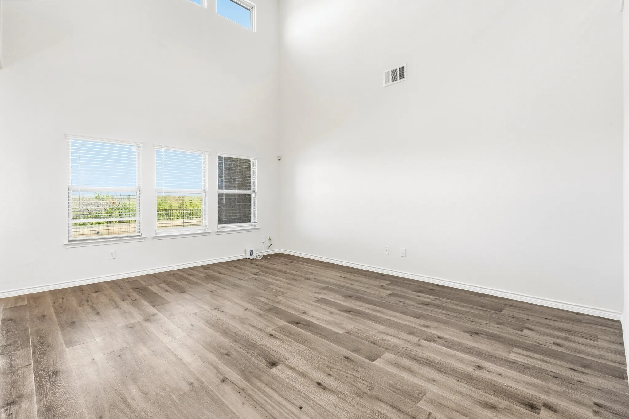 High ceilings, wood-finish flooring, white walls, and multiple windows