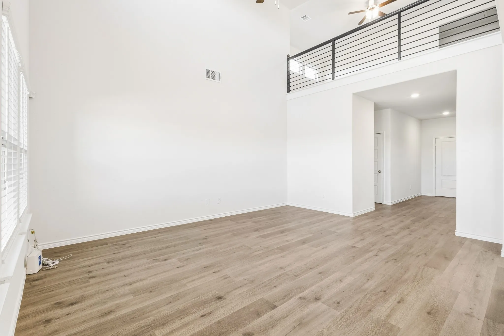Vaulted ceiling, wood-finish flooring, white walls, upper-level railing, and recessed lighting