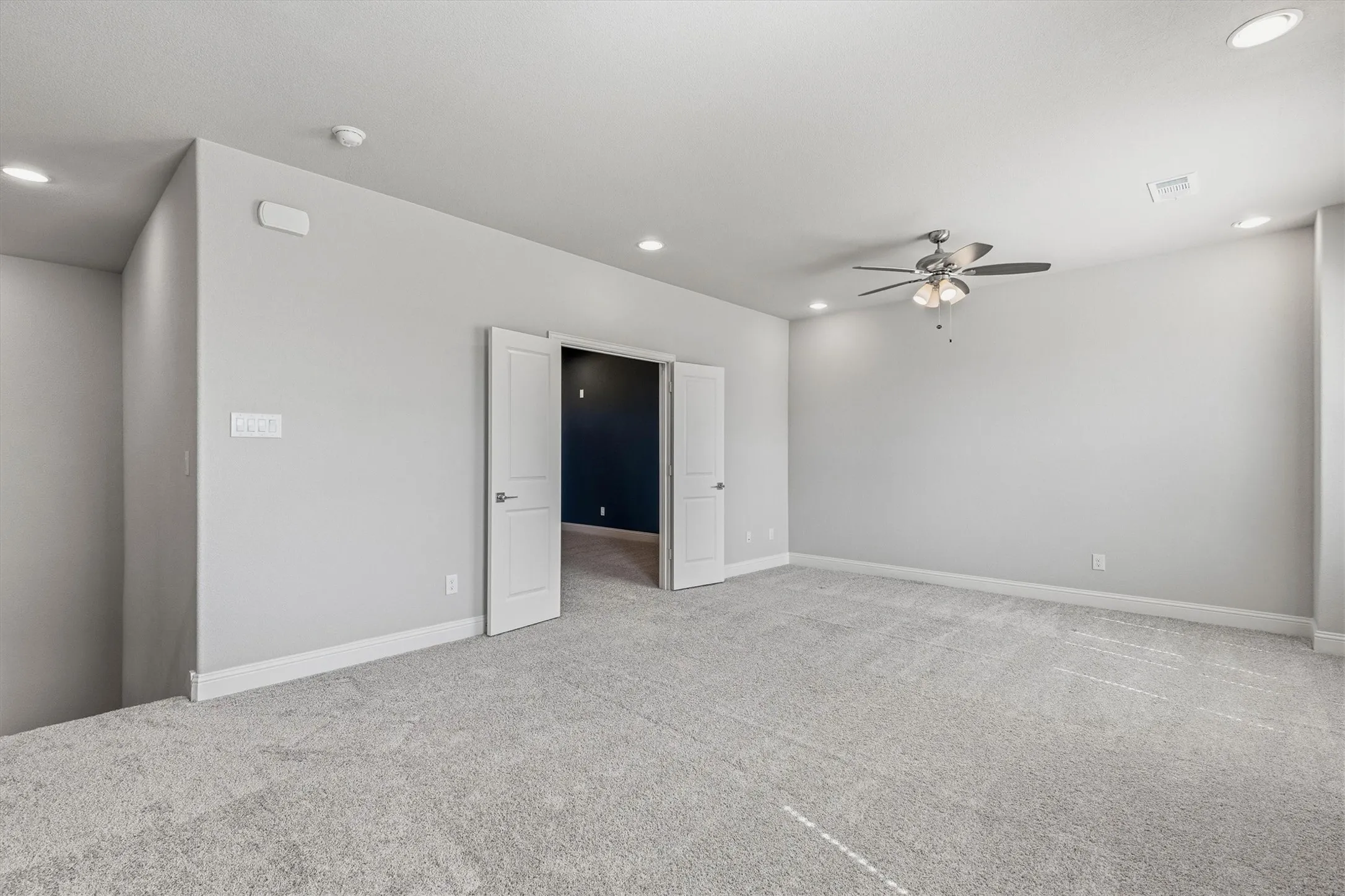 Spacious carpeted room featuring recessed lighting, a ceiling fan, and double panel doors