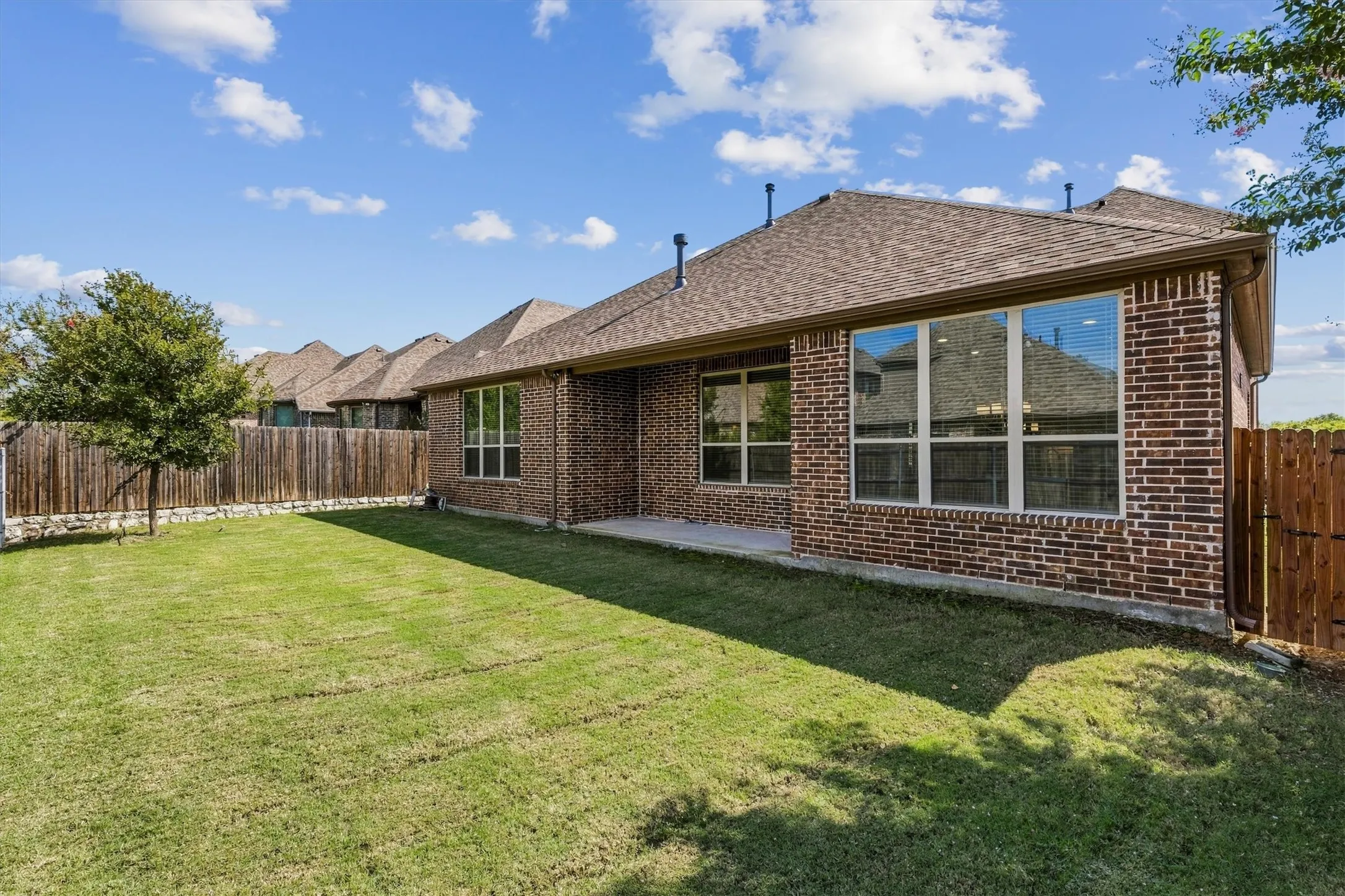 Expansive backyard featuring a manicured lawn, full brick exterior, and a privacy fence