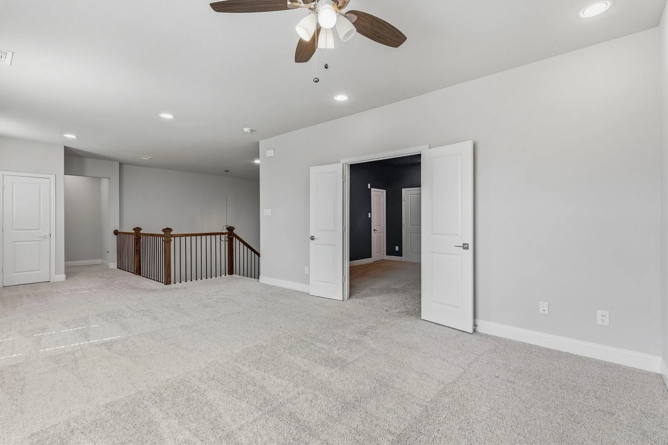 Spacious room with light gray carpeting, recessed lighting, and a ceiling fan