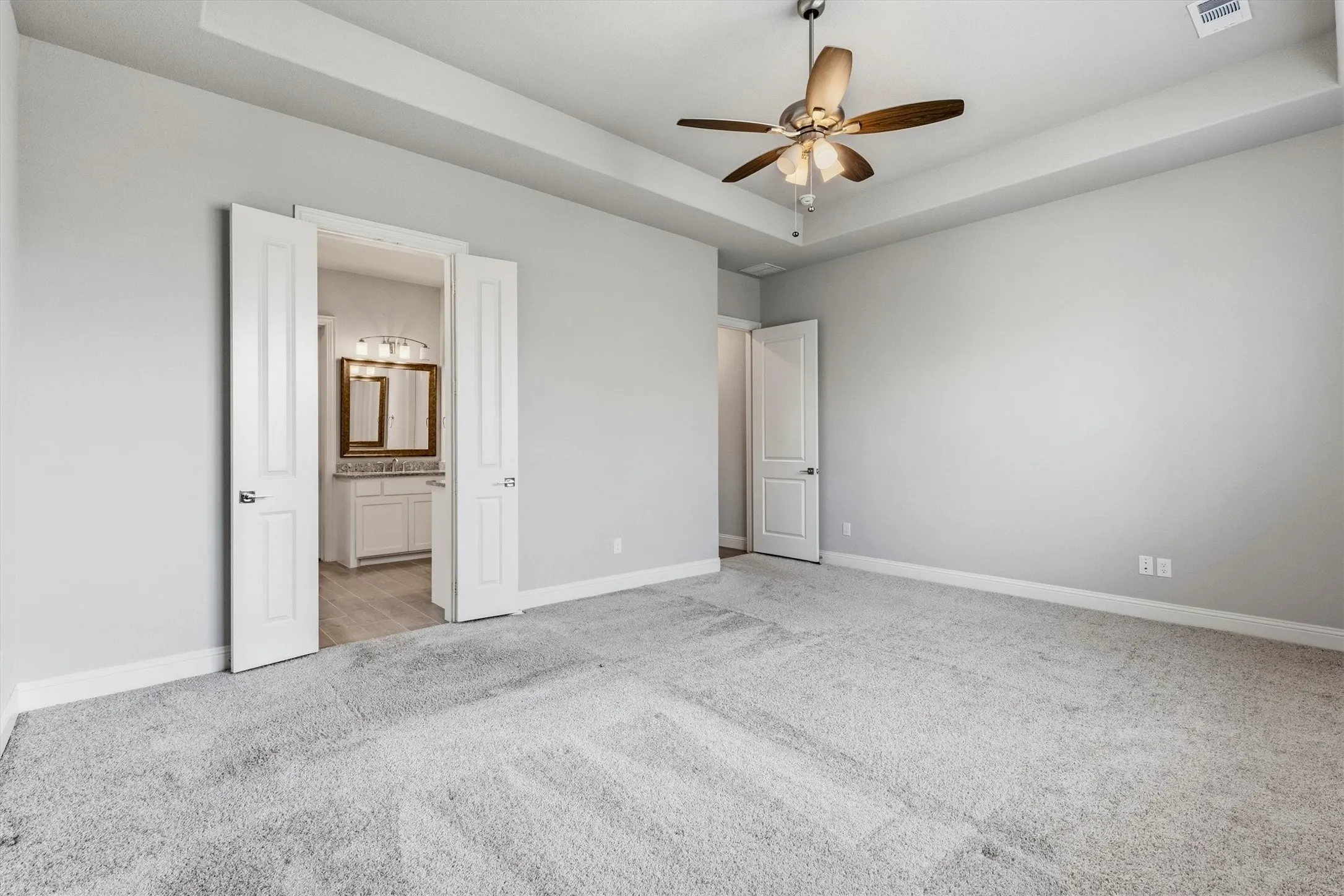 Tray ceiling with a ceiling fan, light gray wall paint, and gray carpeted flooring