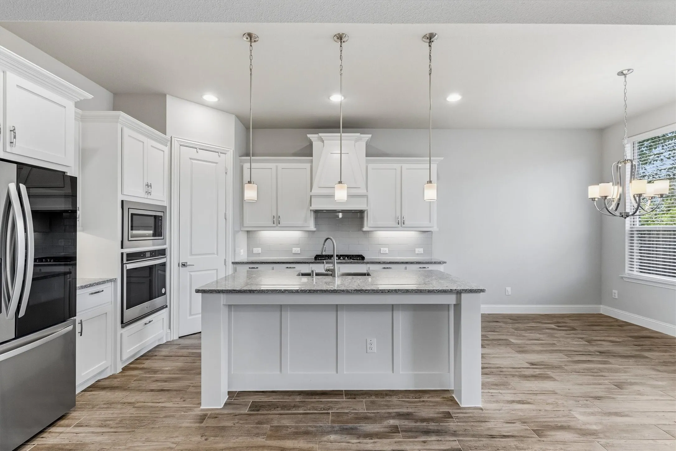 Kitchen featuring a central island with countertop, stainless steel appliances, pendant lighting, and wood-finish flooring