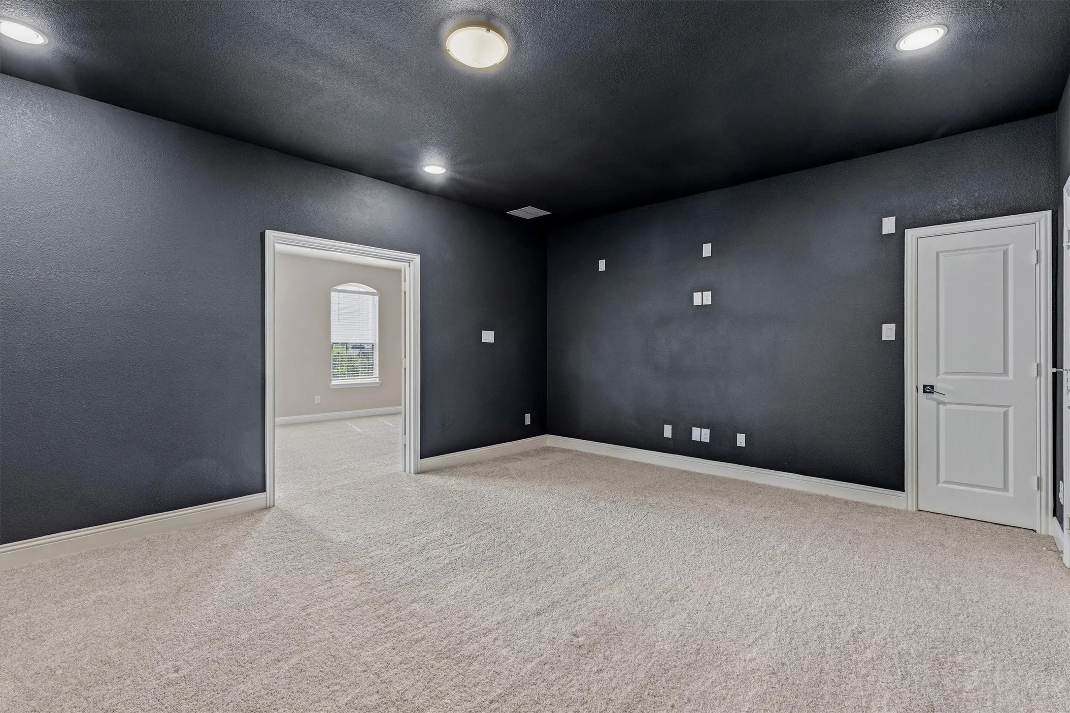 Recessed lighting, flush mount lighting, textured walls, light-toned carpeting, and a white interior door