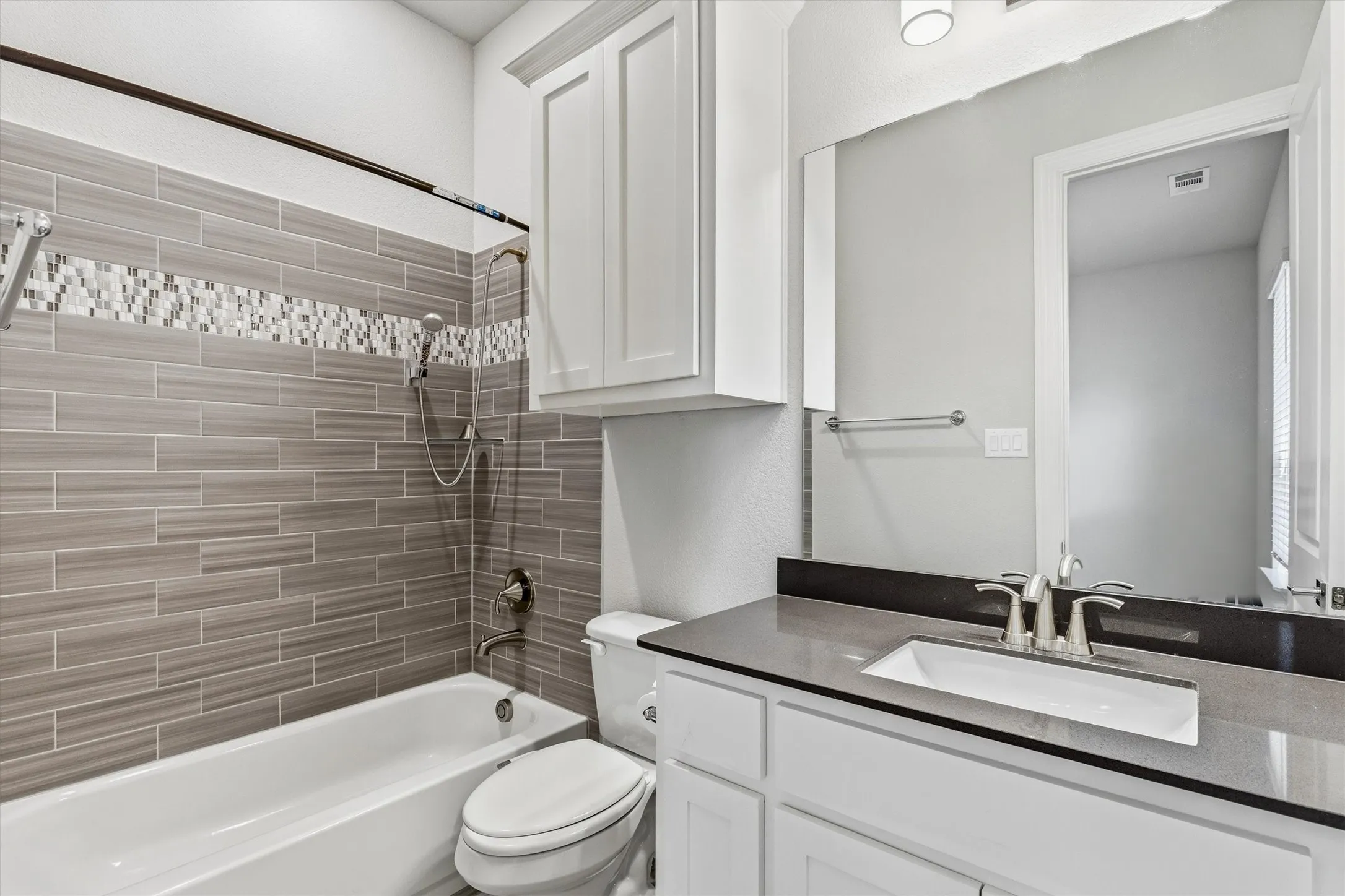 White vanity with an undermount sink, brushed nickel faucet, and a dark stone countertop