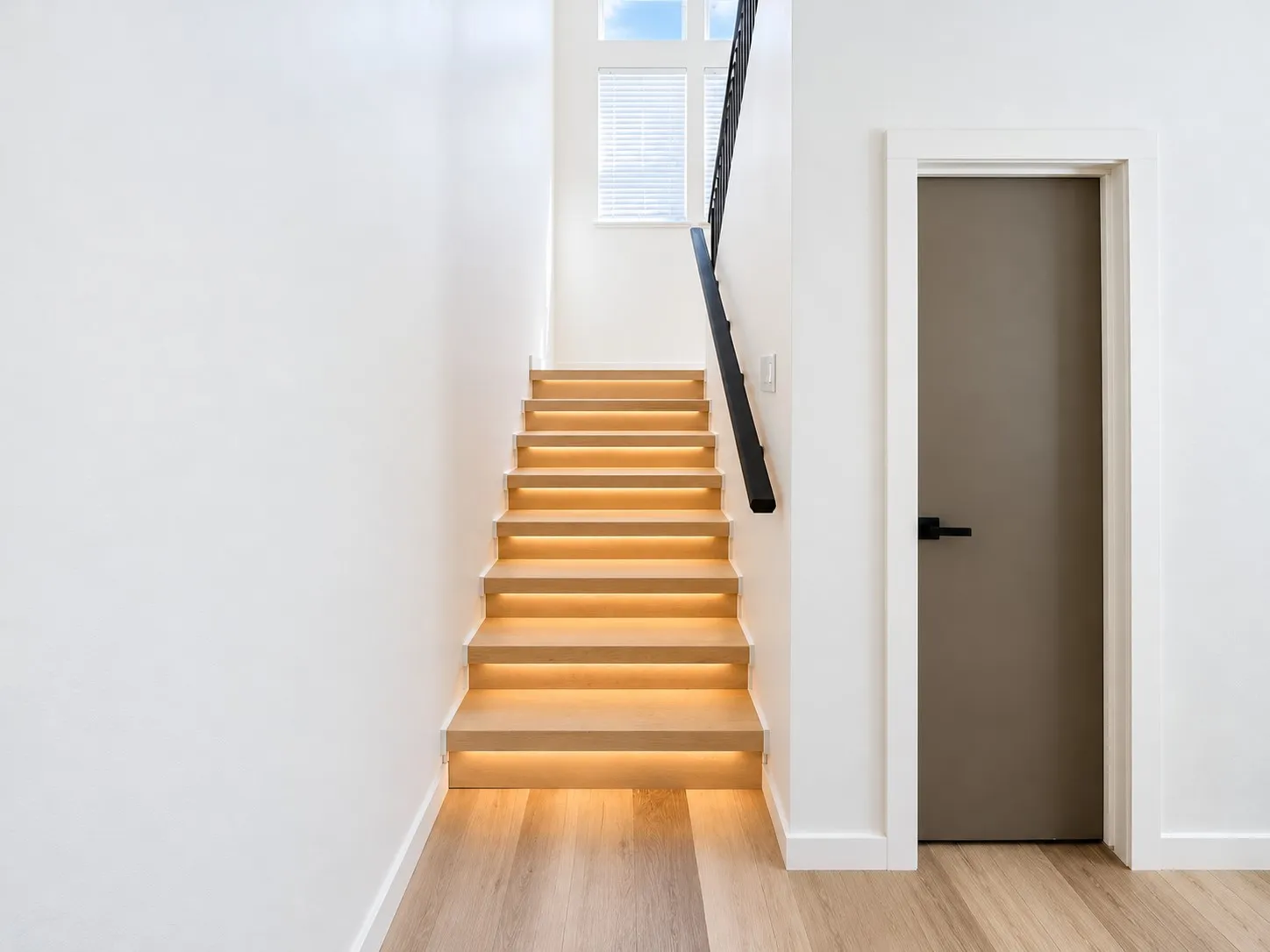 Floating wood-finish staircase with integrated lighting, wood-finish flooring, and a contemporary black handrail