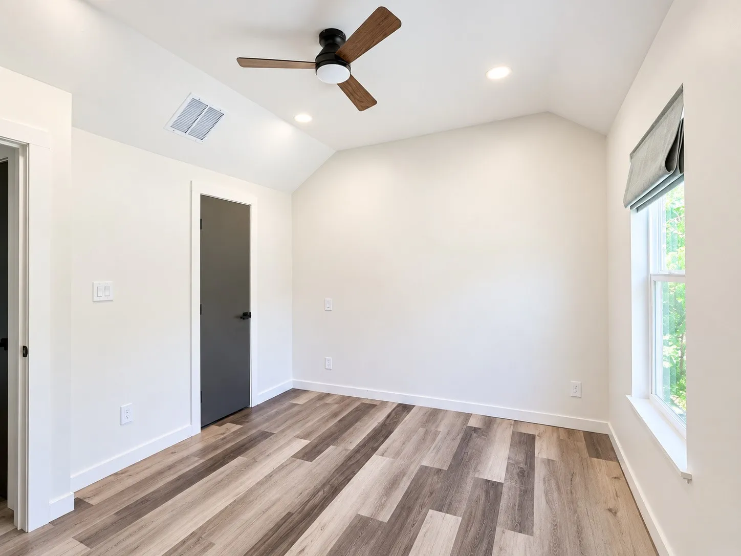 Vaulted ceiling with wood-finish ceiling fan, recessed lighting, wood-finish flooring, and a single window with a privacy shade