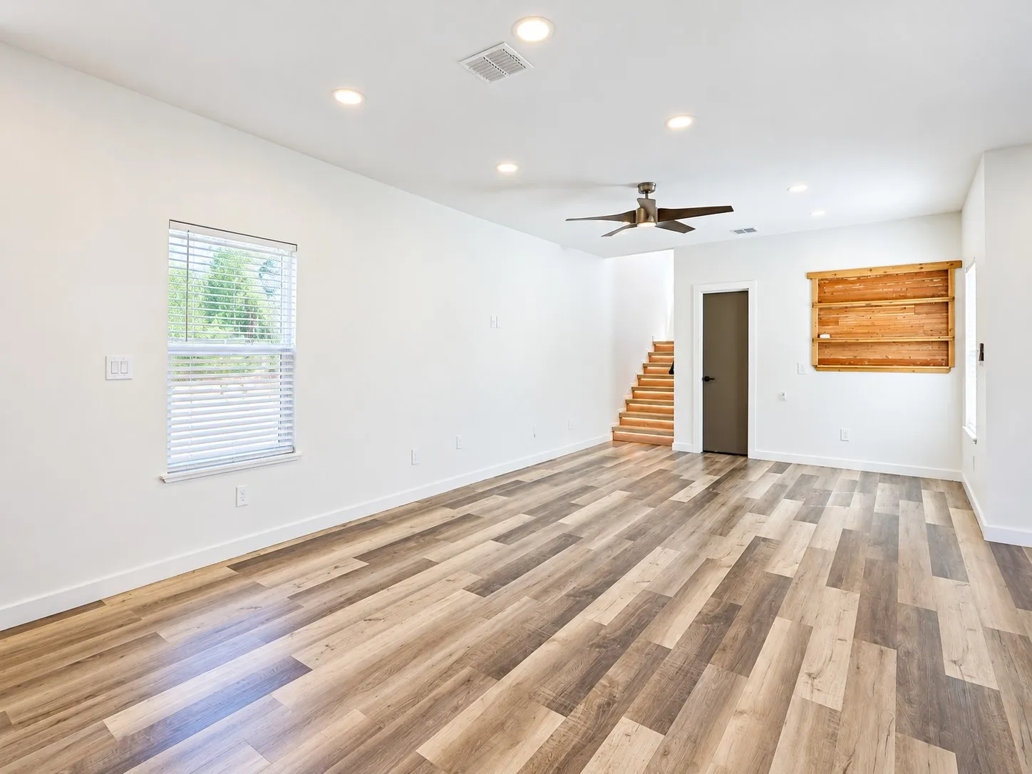 Wood-finish flooring, recessed lighting, ceiling fan, natural wood built-in shelving, and staircase with wood treads