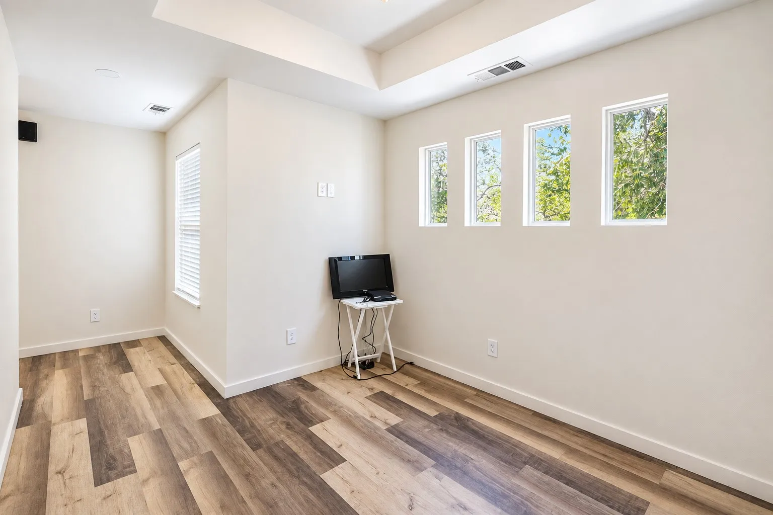 Wood-finish flooring with a multi-toned pattern, recessed ceiling lighting, and multiple windows
