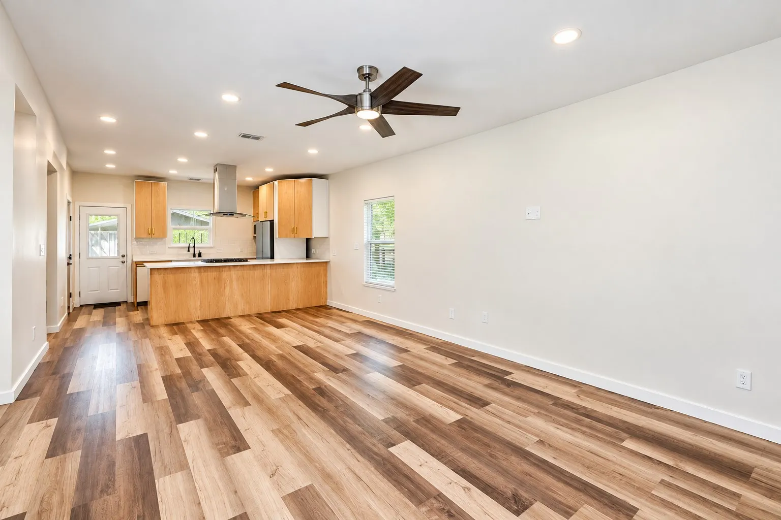 Open-concept living area with wood-finish flooring, recessed lighting, and a ceiling fan