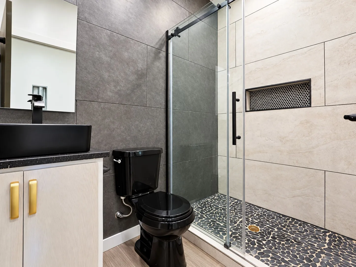 Walk-in shower with a mosaic pebble floor, tiled walls, and a recessed niche