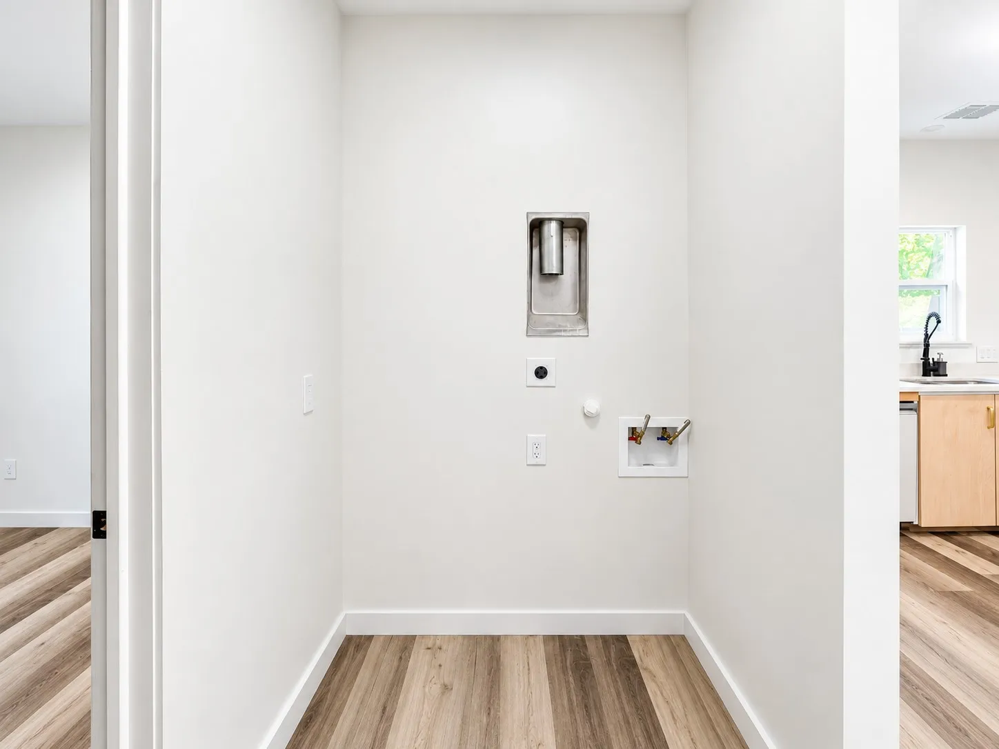 Dedicated utility space featuring wood-finish flooring and white walls