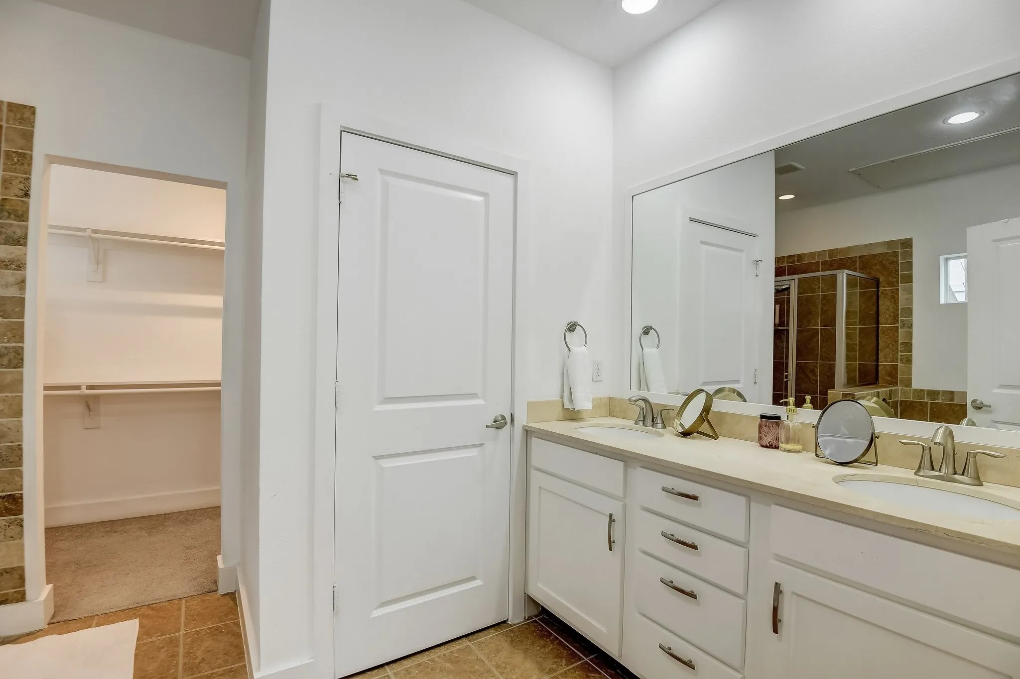 Full bath featuring a shower stall, double vanity, a spacious closet, and tile patterned floors