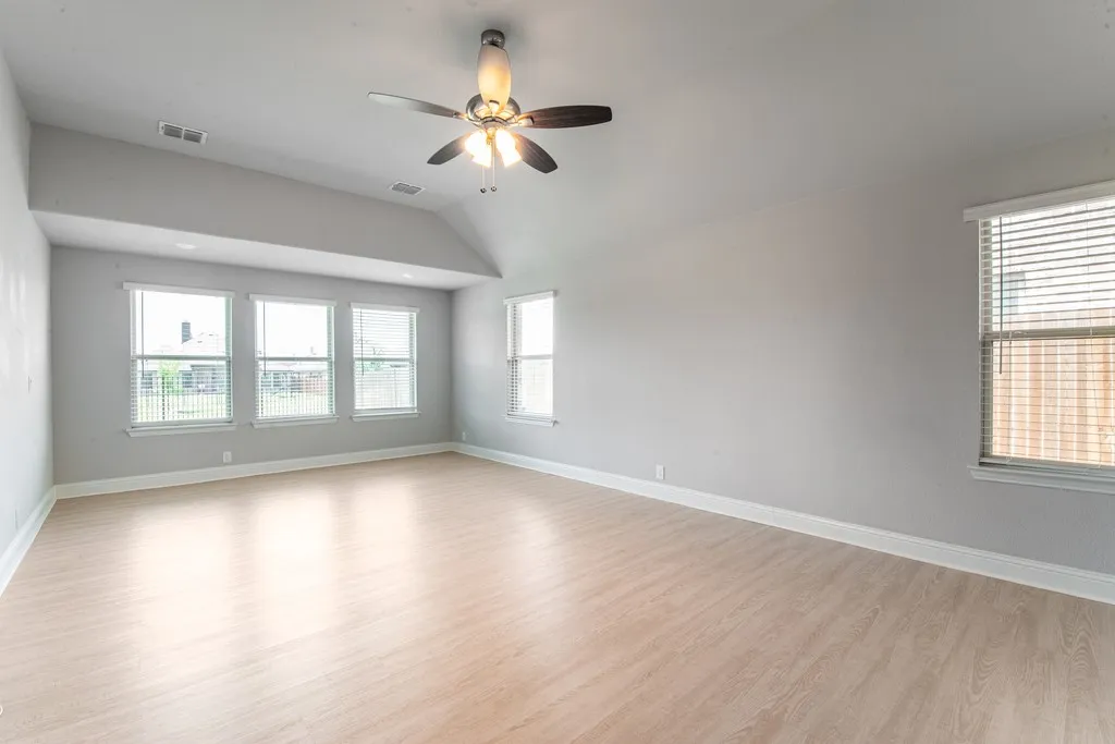 Vaulted ceiling with a ceiling fan, recessed lighting, wood-finish flooring, and multiple windows
