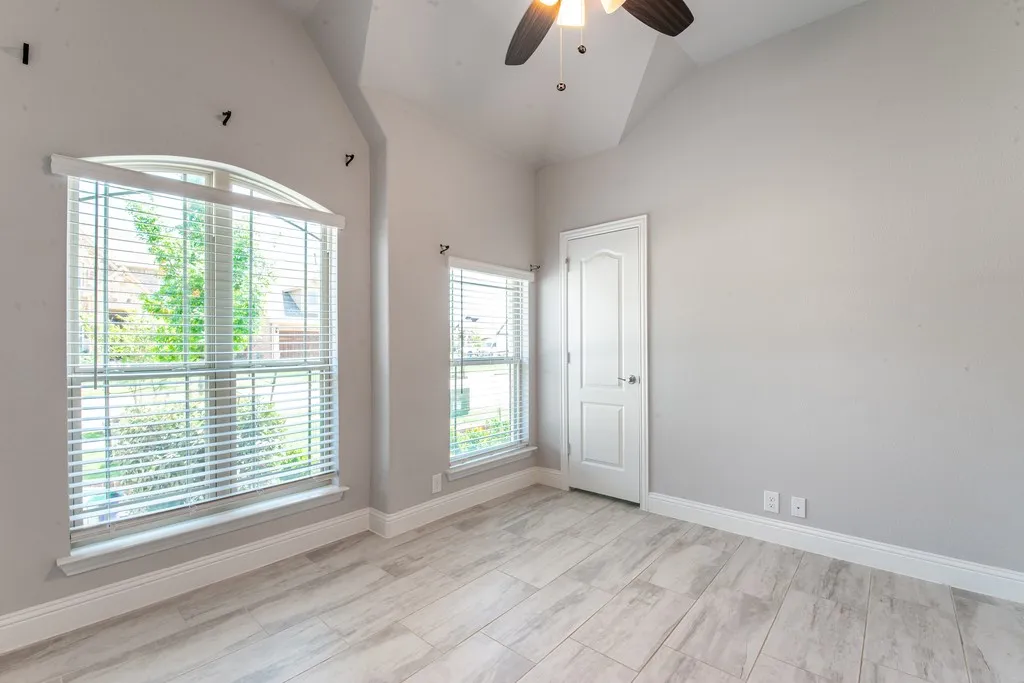 Vaulted ceiling with a ceiling fan, wood-finish flooring, and white trim throughout