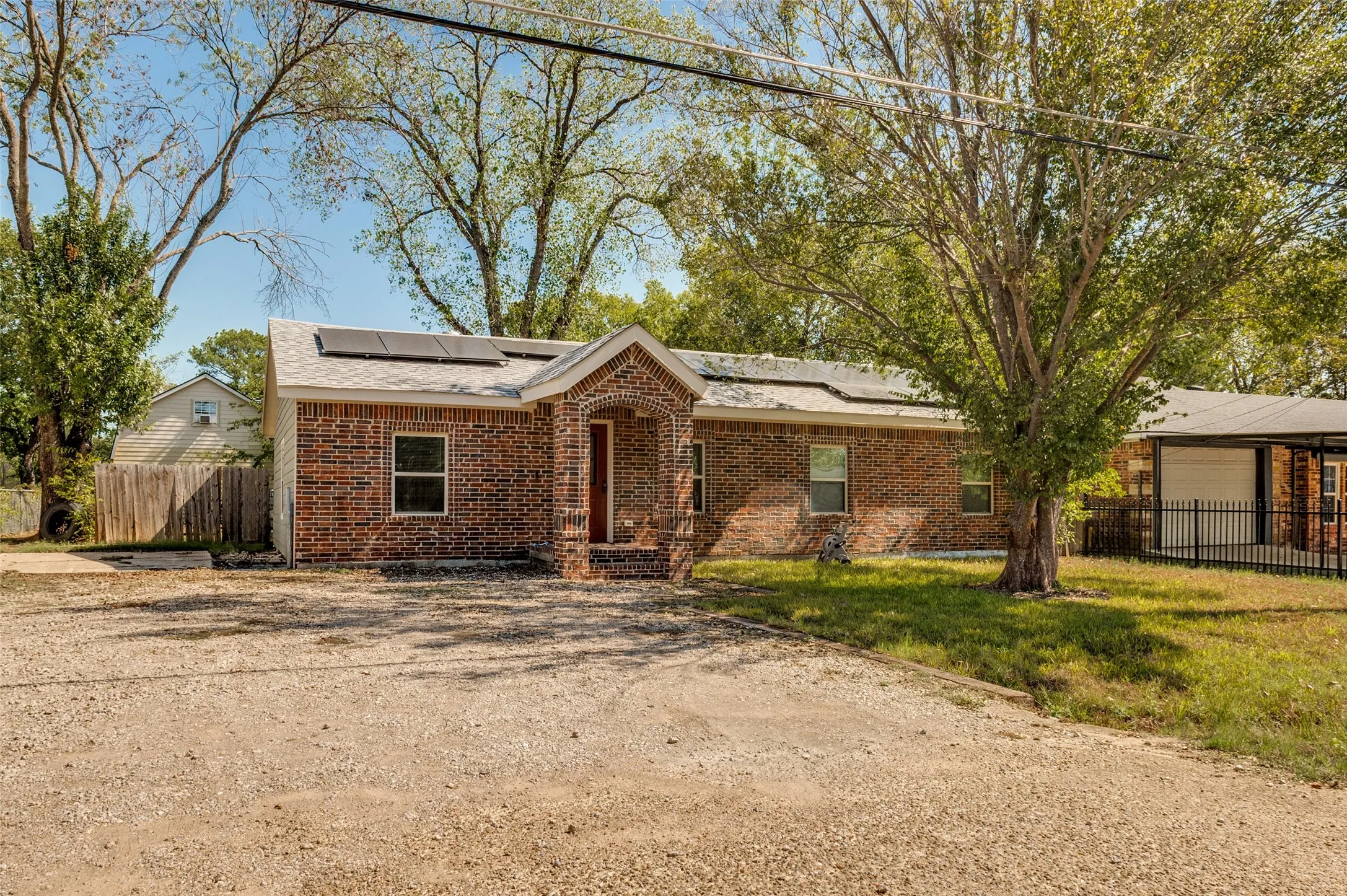 Brick exterior with covered front entry and a gravel driveway