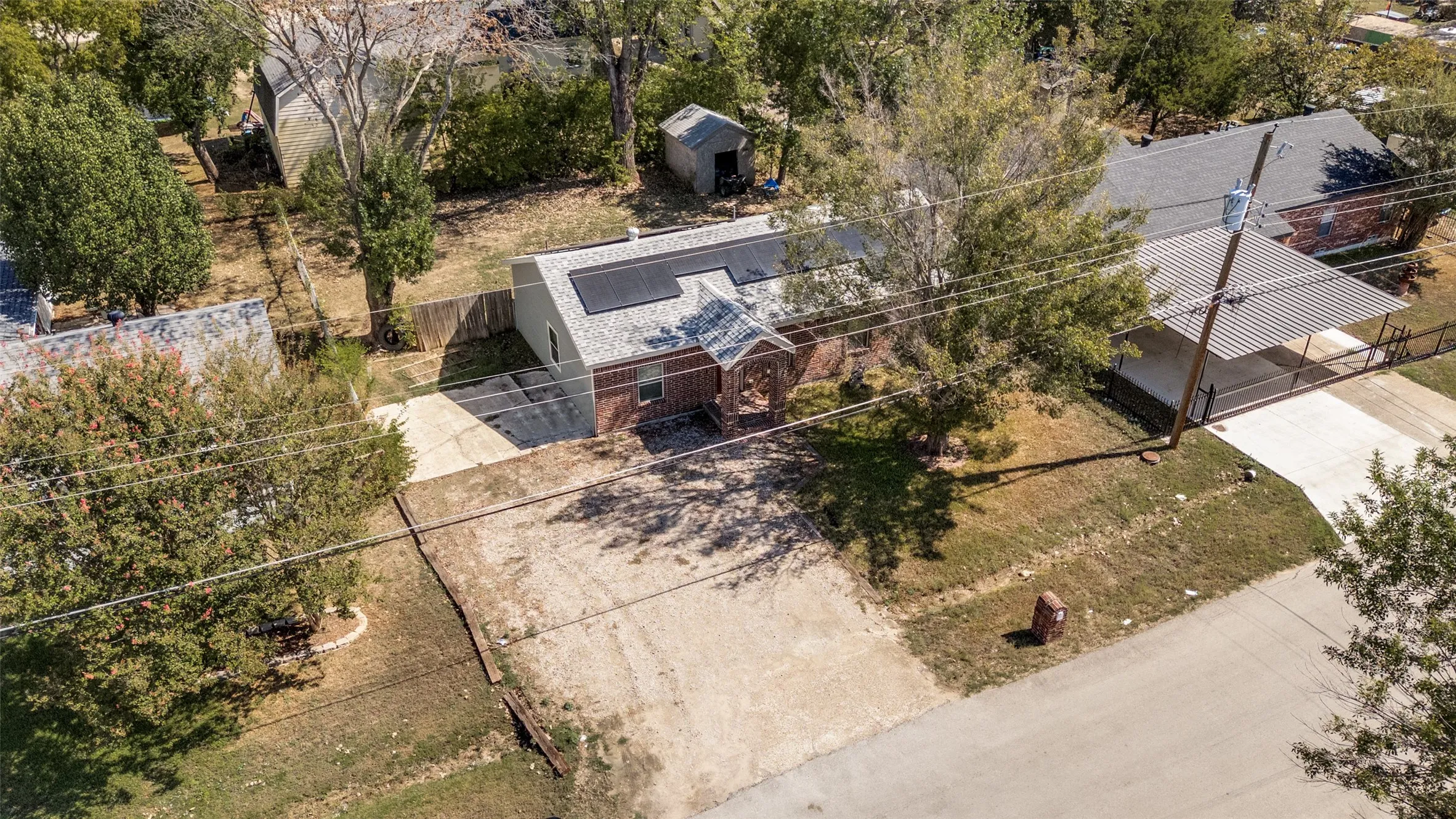 Brick exterior with solar panels, an attached carport, and a detached shed