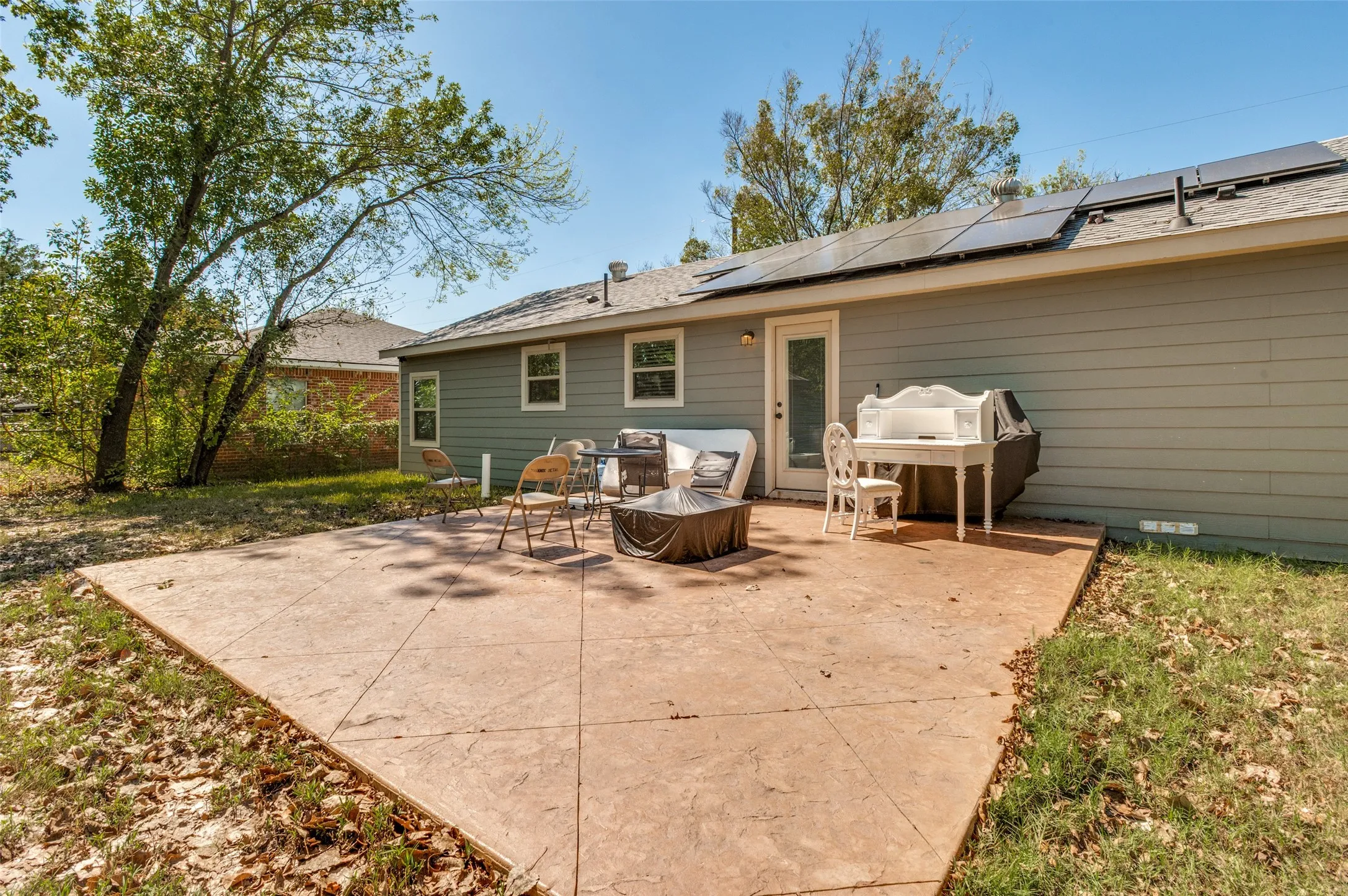 Expansive concrete patio with a textured finish, bordered by green landscaping