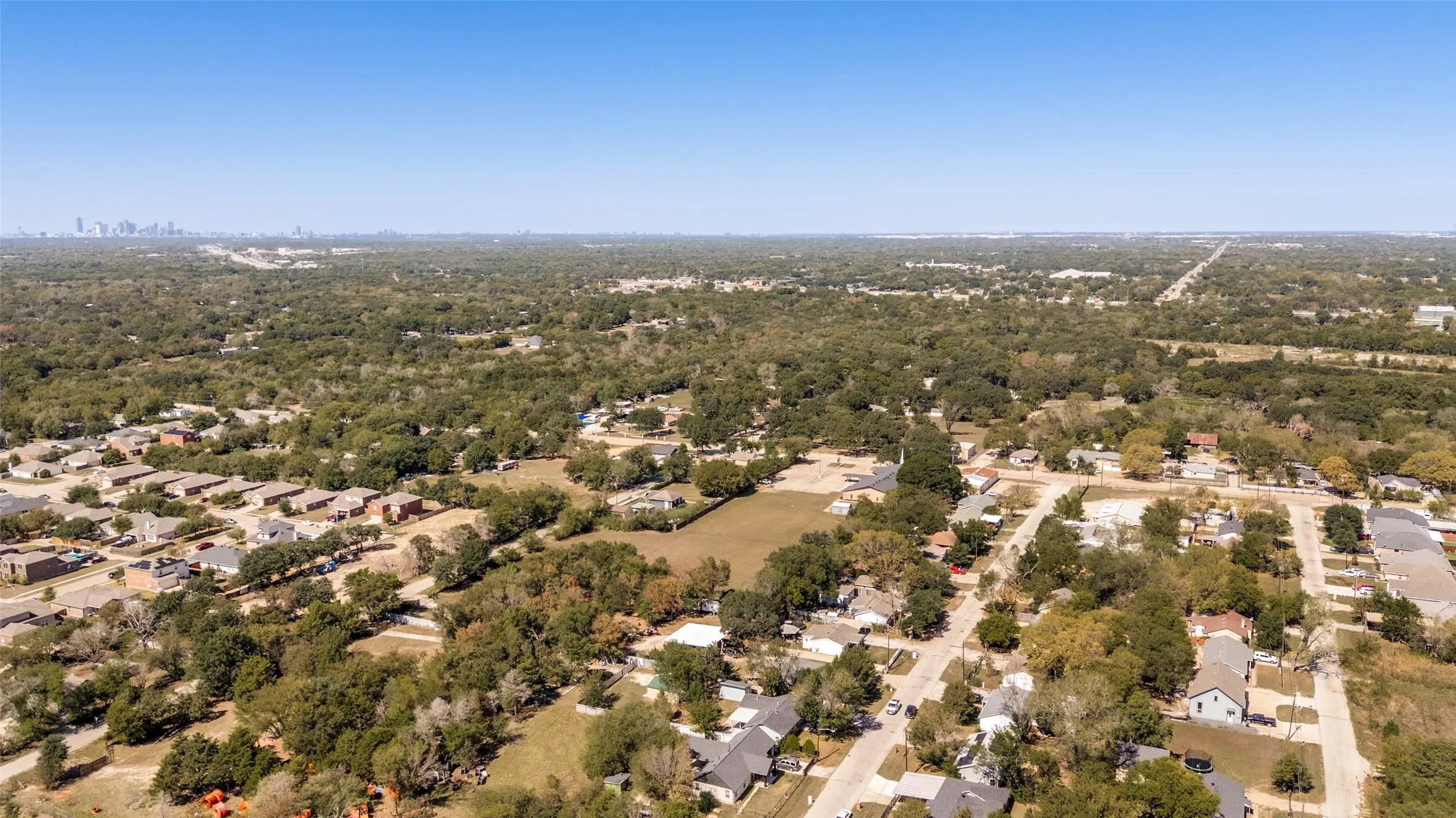 Aerial perspective of a tree-lined residential area with a distant city skyline