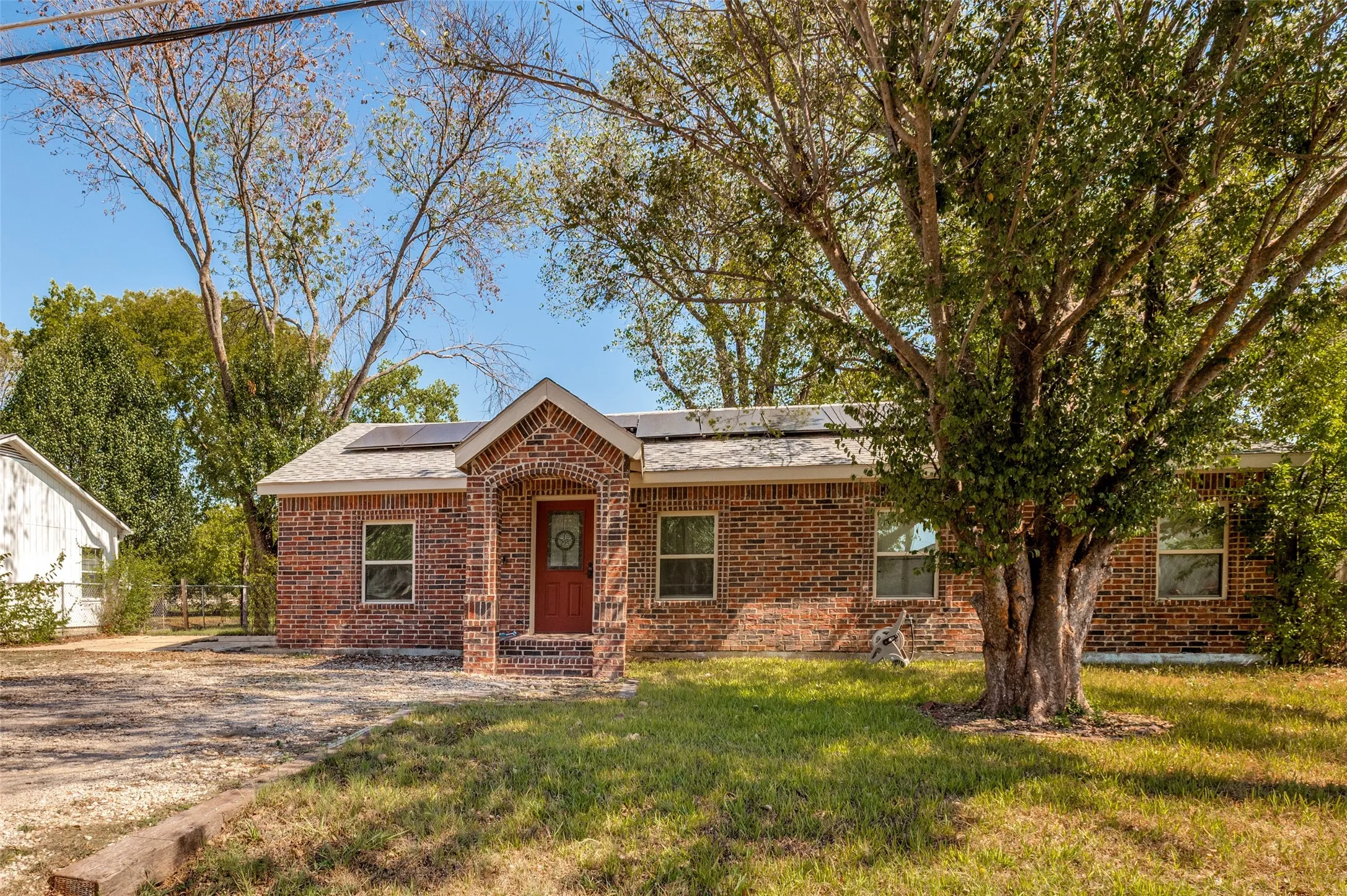 Brick exterior with an arched entry, solar panels, and a red front door