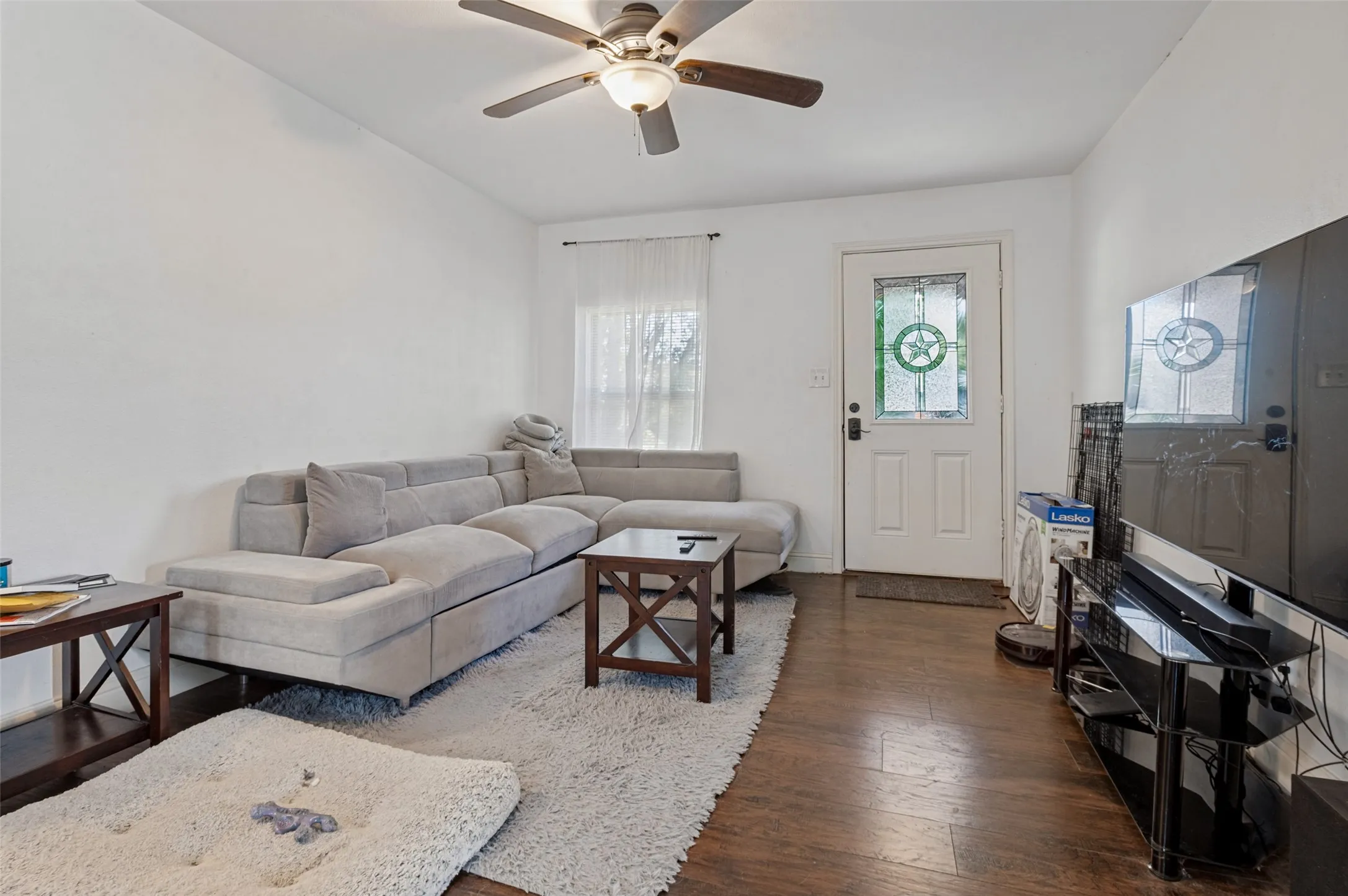 Wood-finish flooring, white walls, ceiling fan with light fixture, and a white entry door with decorative glass inserts