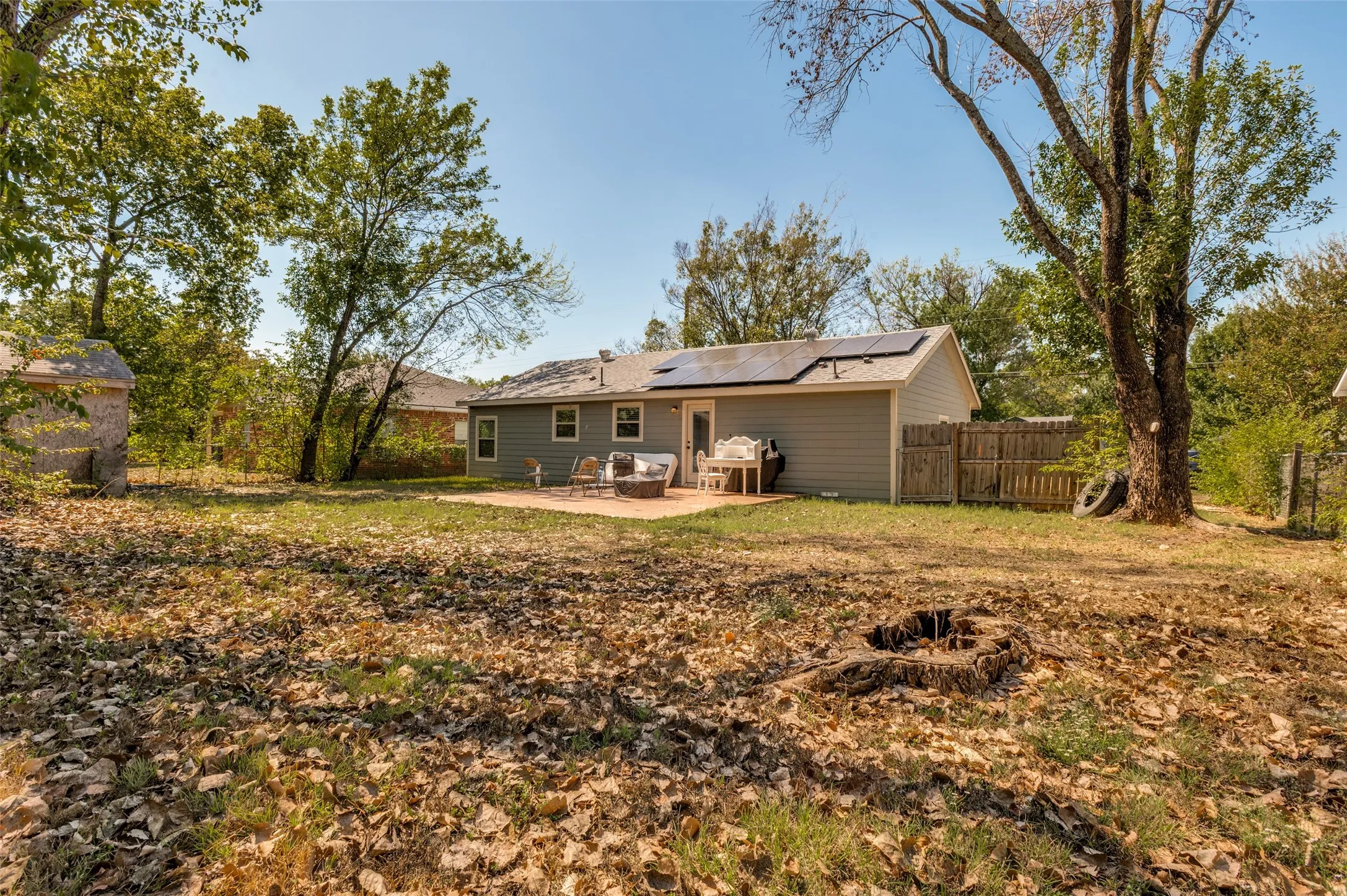 Expansive rear yard featuring a concrete patio, exterior siding, and solar panels