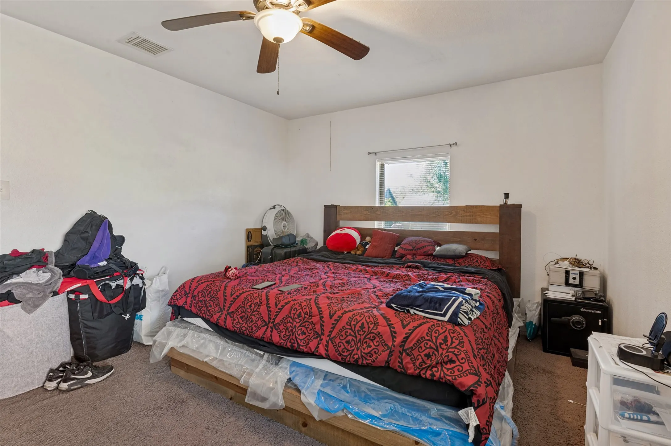Carpeted flooring, white painted walls, ceiling fan with integrated lighting, and a window providing natural illumination