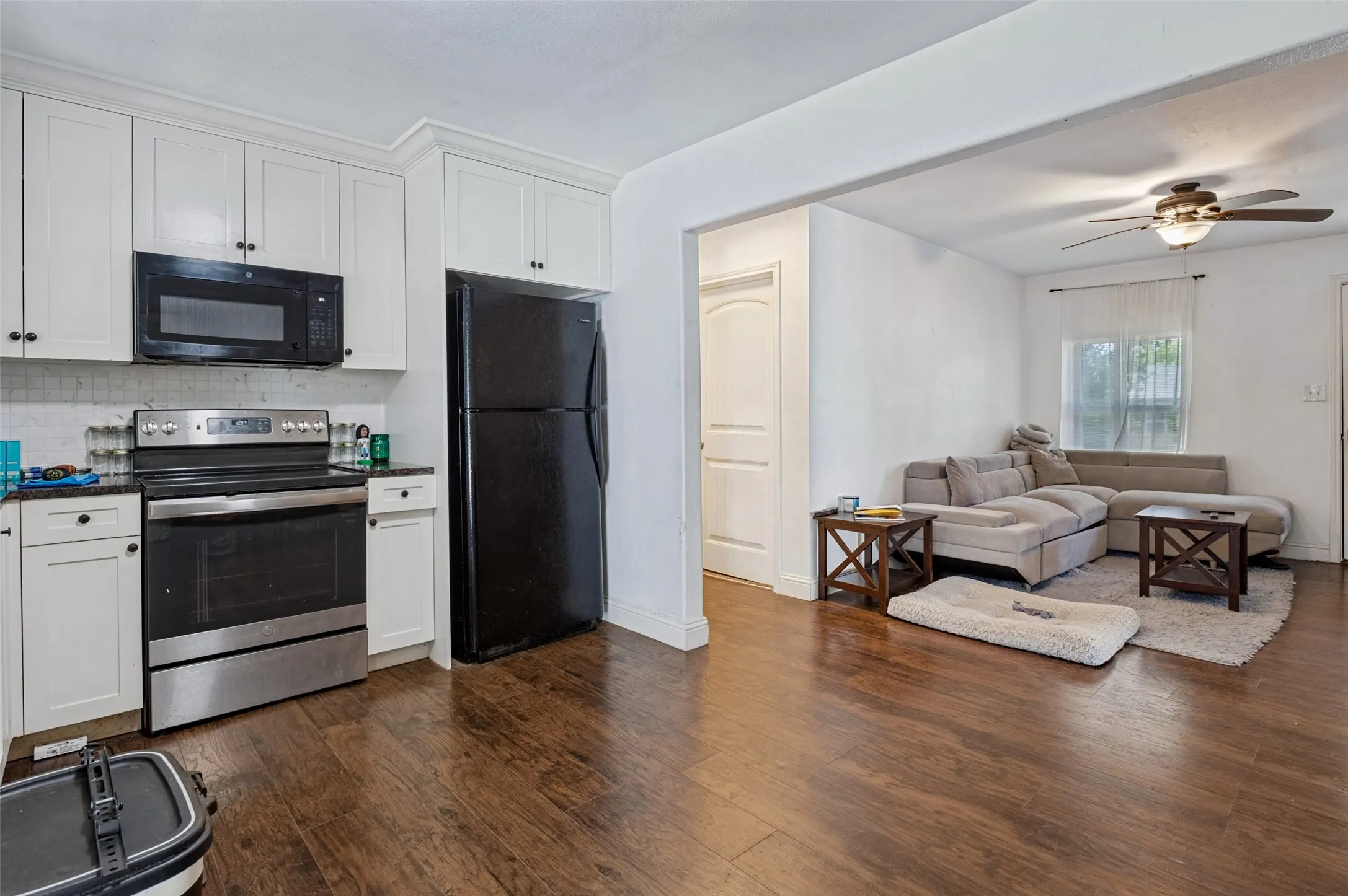 Kitchen featuring white upper and lower cabinetry, dark countertops, stainless steel range, and a built-in microwave