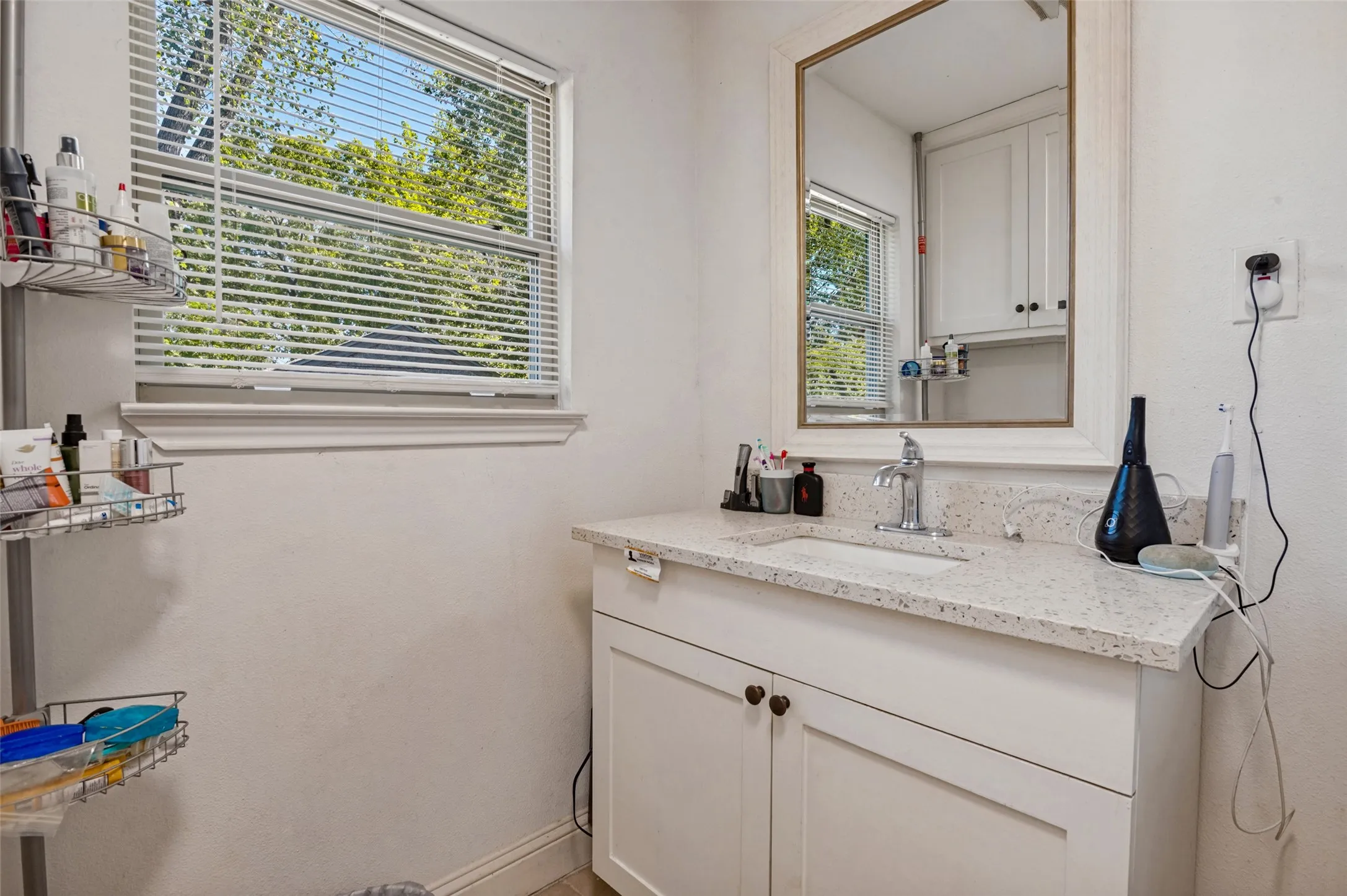 Vanity with an integrated sink, quartz countertop, and white shaker-style cabinetry