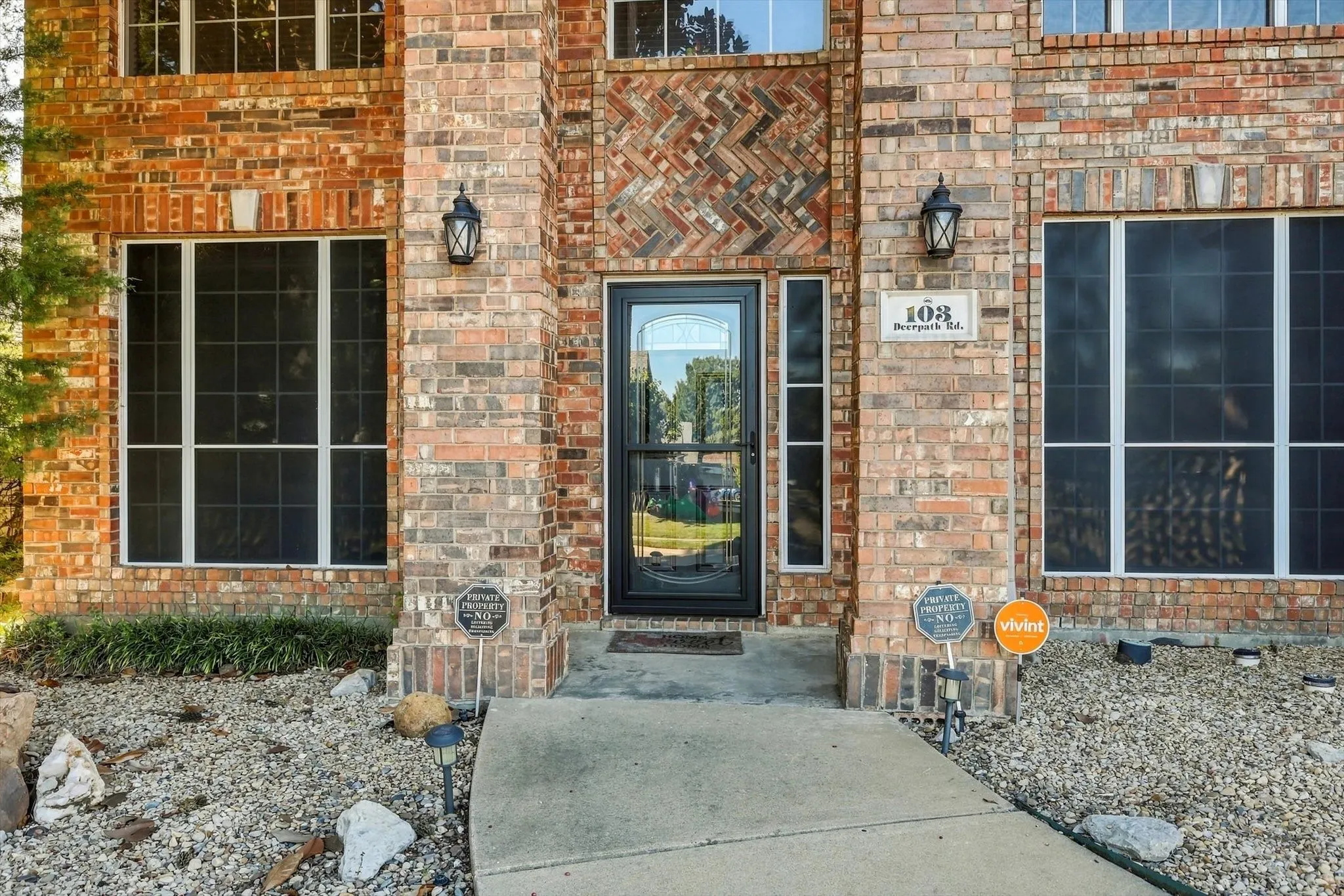 Brick exterior with decorative brickwork accents, multiple windows with white framing, and a central entry door with a sidelight