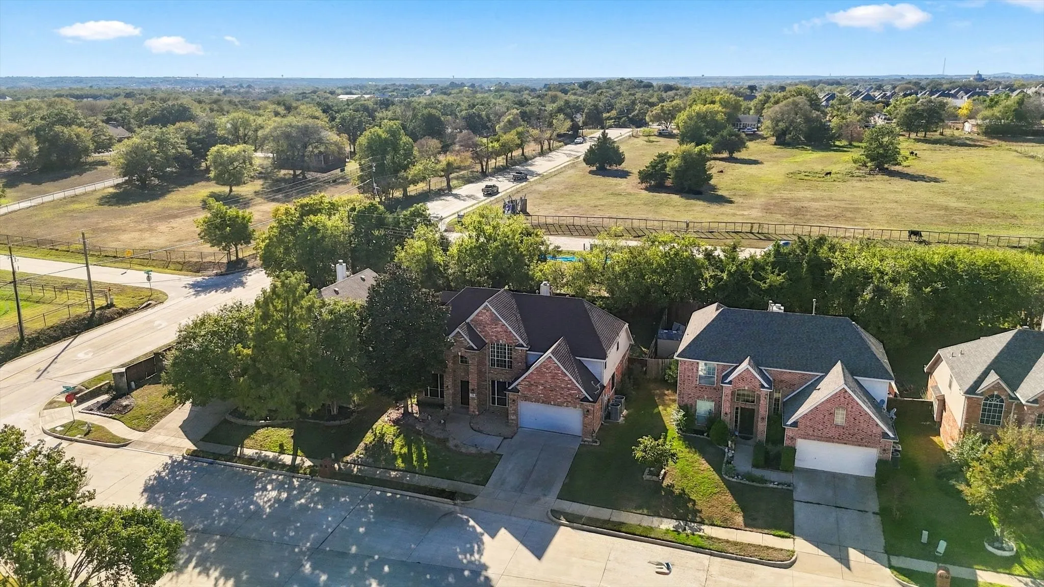 Two-story residences featuring brick and siding exteriors, attached garages, and mature landscaping, situated on a residential street
