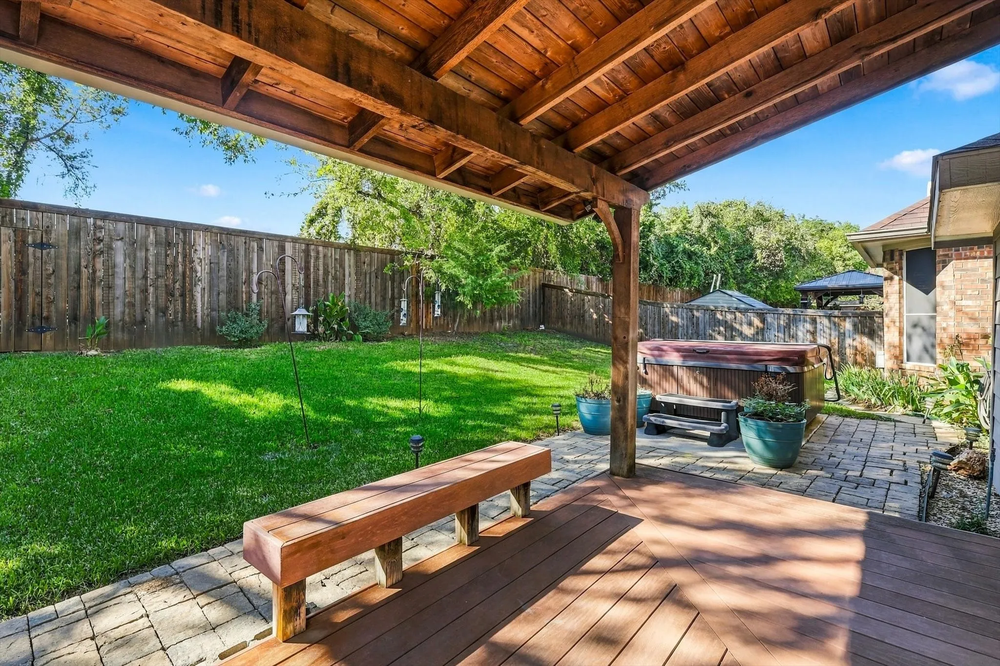 Covered patio with a wood-finish ceiling, composite decking, and a built-in spa