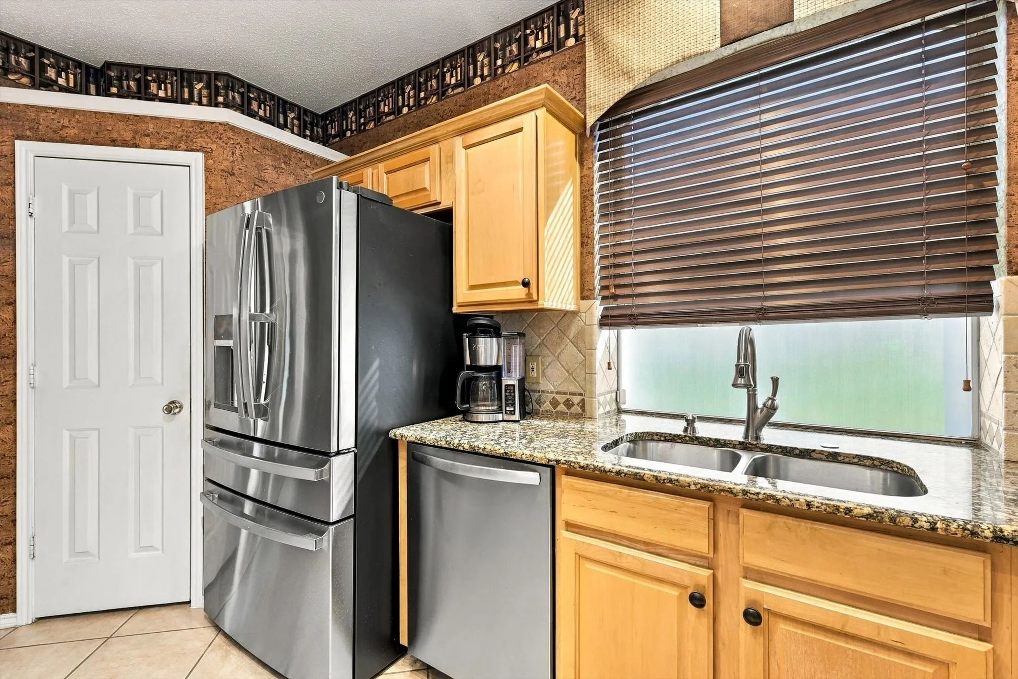 Stainless steel appliances, wood-finish cabinetry, granite countertops, double basin sink, and window blinds