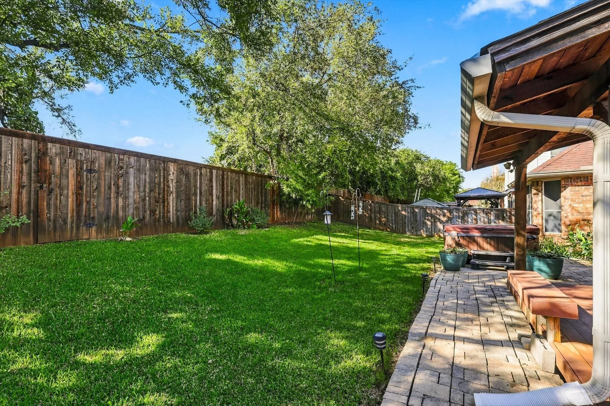 Expansive backyard featuring a lush lawn, wood privacy fence, and mature trees