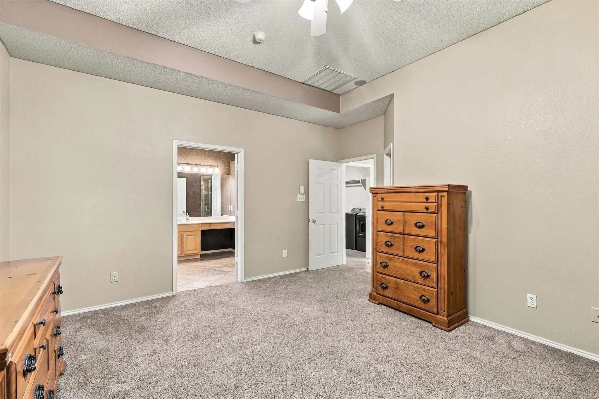 Plush carpeted flooring, vaulted ceiling, ceiling fan with light fixture, and neutral wall tones