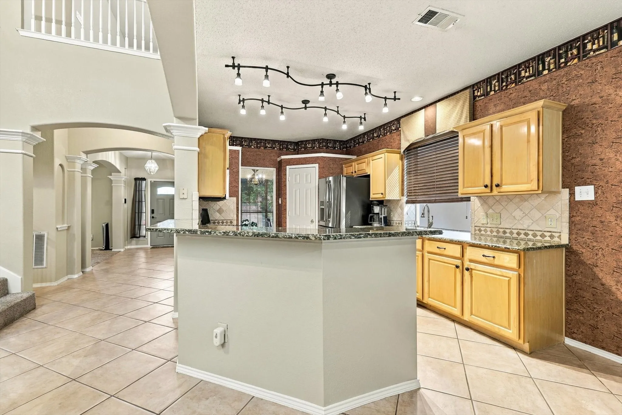 Kitchen featuring light wood cabinetry, tiled backsplash, and granite-look countertops