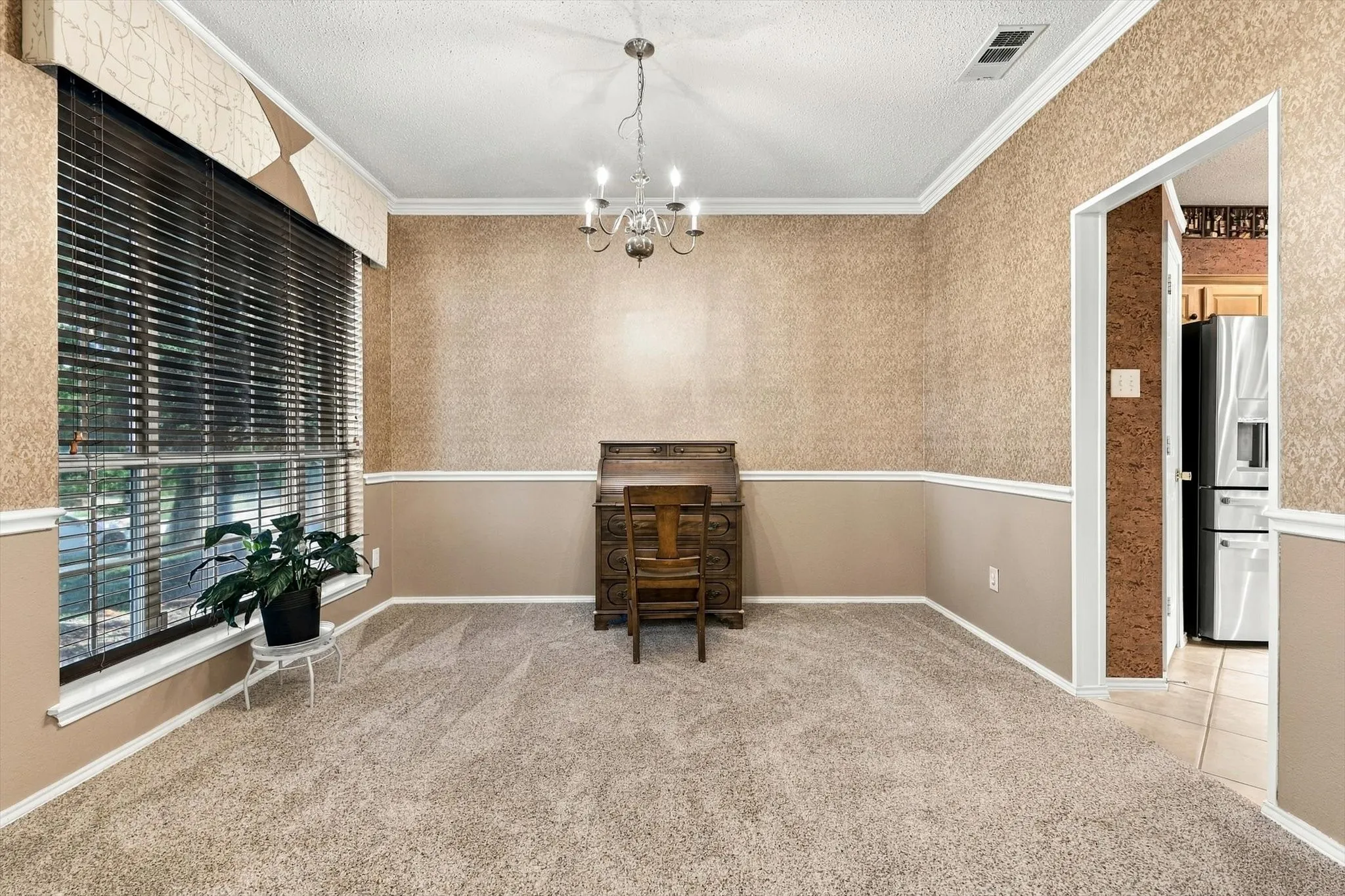 Recessed ceiling, crown molding, chandelier lighting, large window with blinds, and neutral carpet flooring