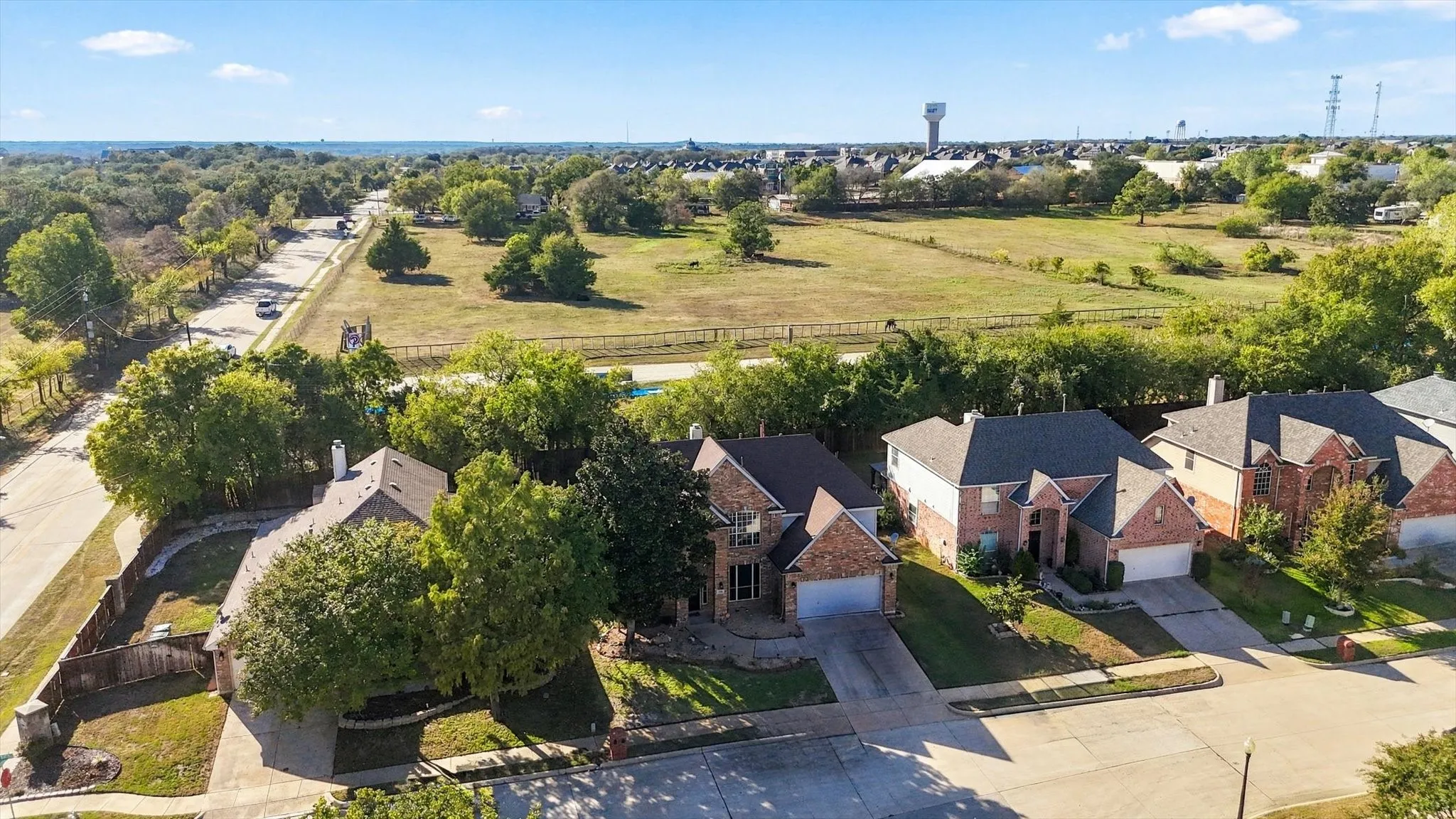 Aerial perspective showcasing a residential street, multiple properties with brick exteriors, and surrounding natural areas
