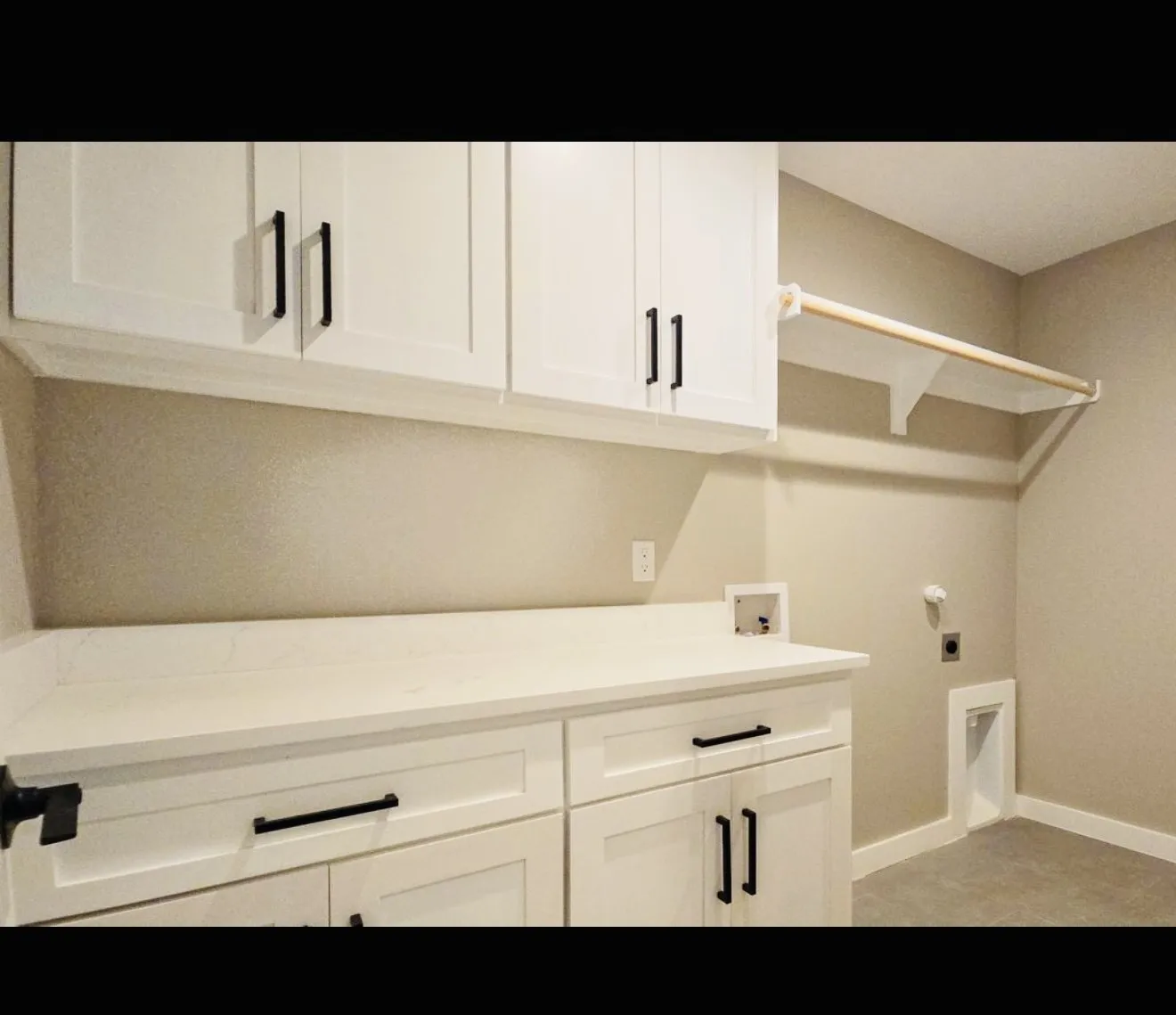White shaker-style cabinetry with matte black hardware, white countertop, and a built-in hanging rod