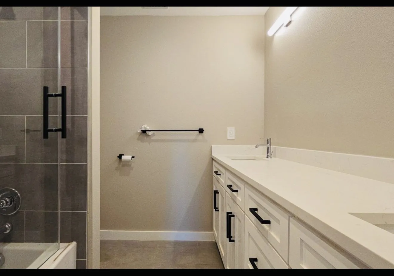 Dual vanity with white cabinetry, matte black hardware, and a light-toned countertop