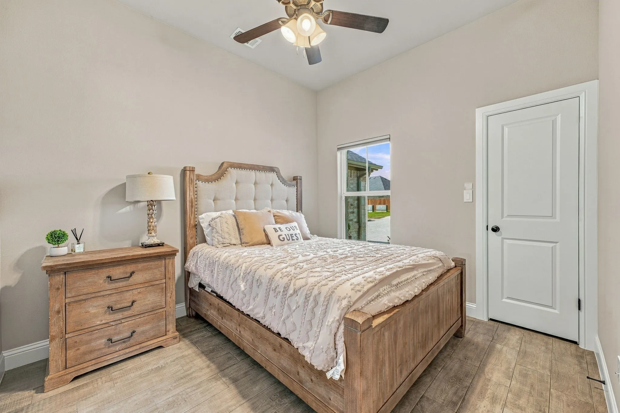 Wood-finish flooring throughout, vaulted ceiling, ceiling fan with integrated lighting, and a white paneled door